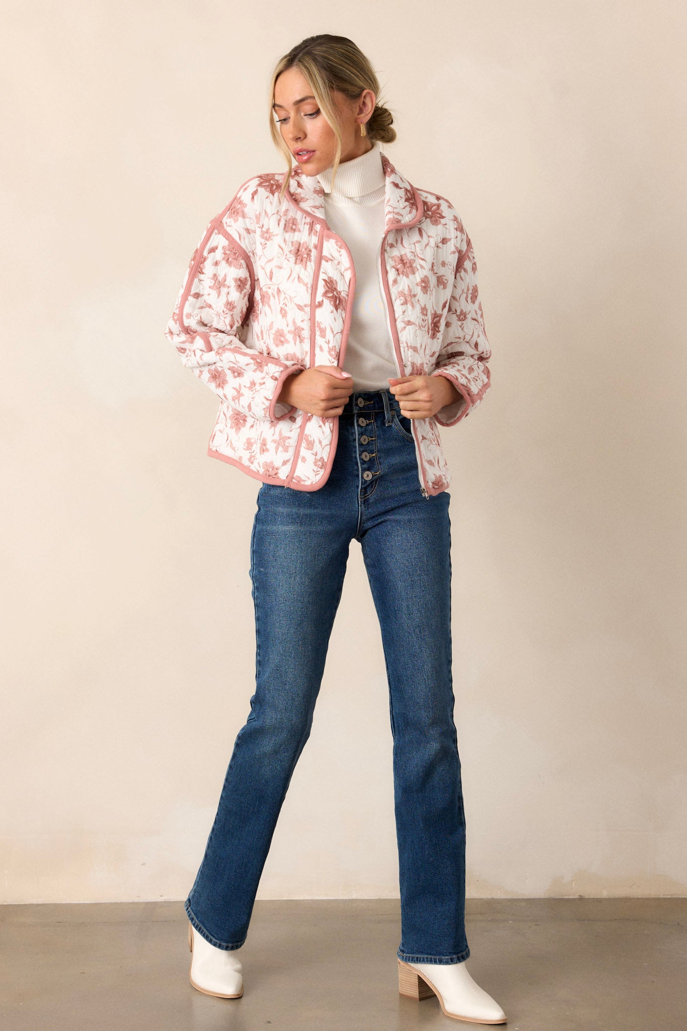 Full body view of this dusty pink jacket that features a collared neckline, a full zip front, a solid dusty pink trim, an ivory floral print, a soft quilted material and snap buttons for extra support.