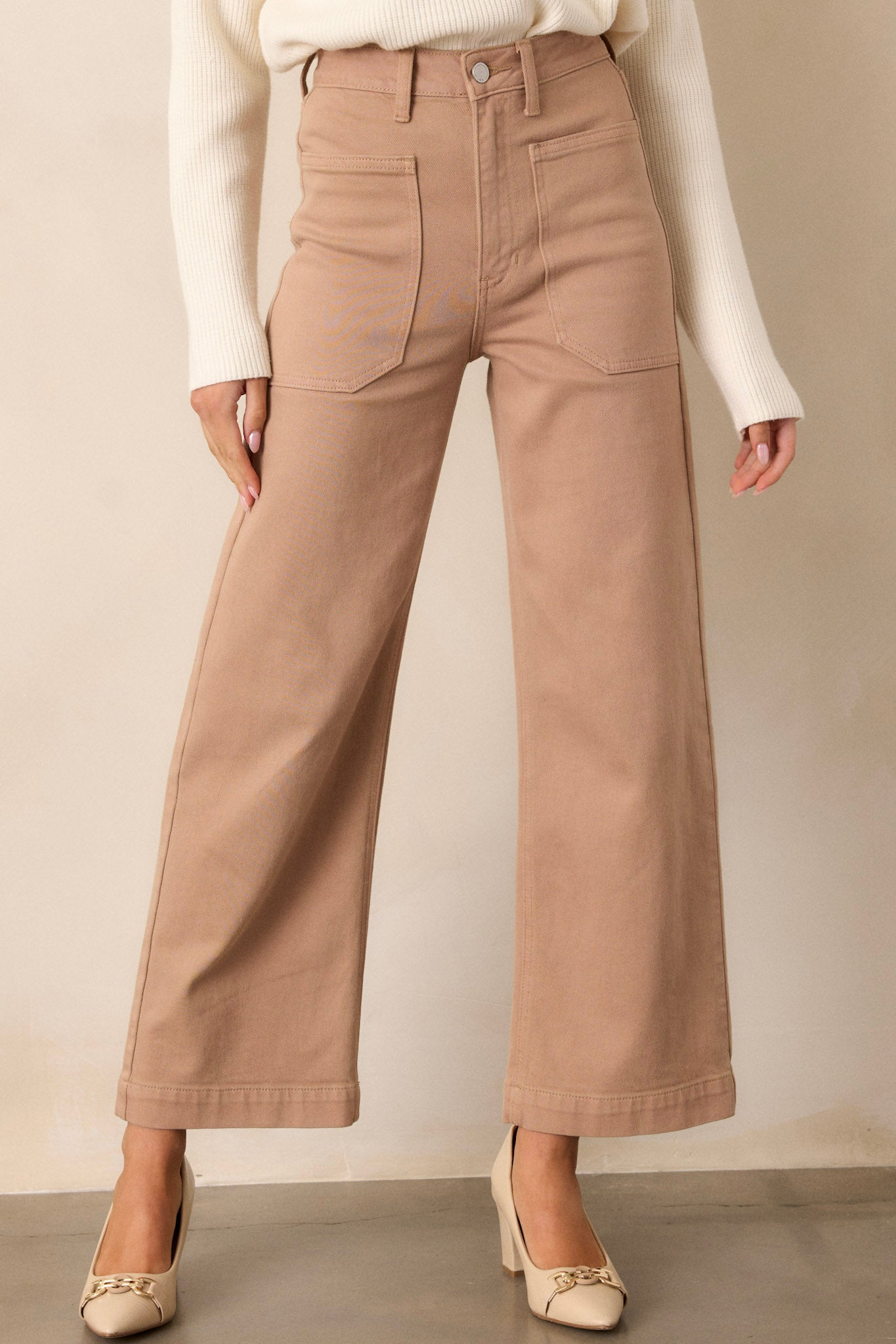 Angled front view of tan jeans featuring a high waisted design, button & zipper closure, belt loops, functional front & back pockets, and a wide leg.