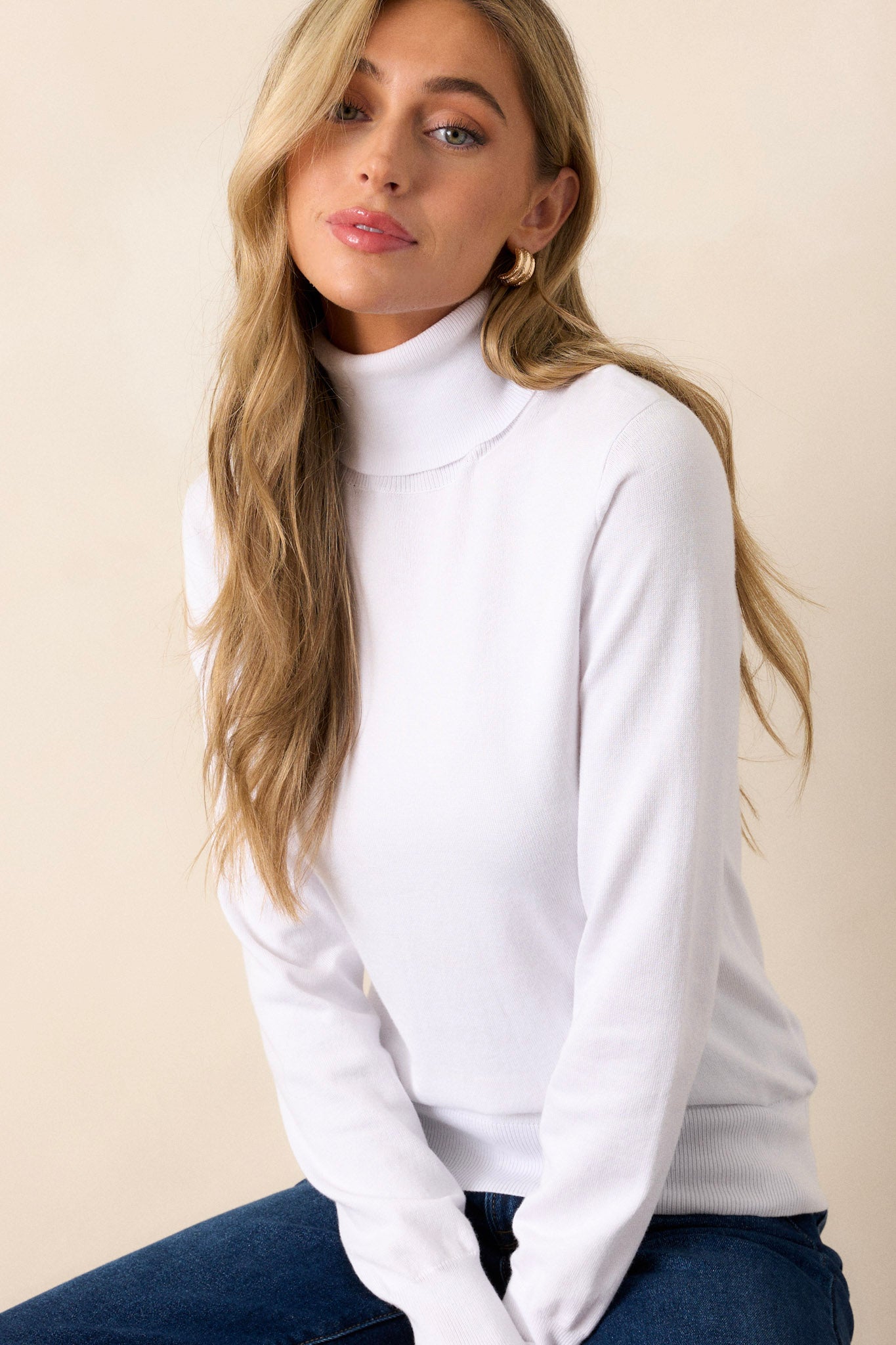 This white sweater has a turtle neckline, long sleeves with ribbed cuffs, a ribbed bottom hem that tapers in, and a super soft feel.