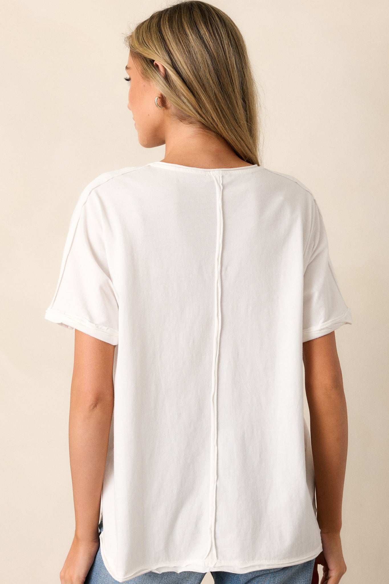 Back view of the top showcasing the vertical hem detail and relaxed fit. The clean design and short sleeves create a simple yet elegant silhouette.