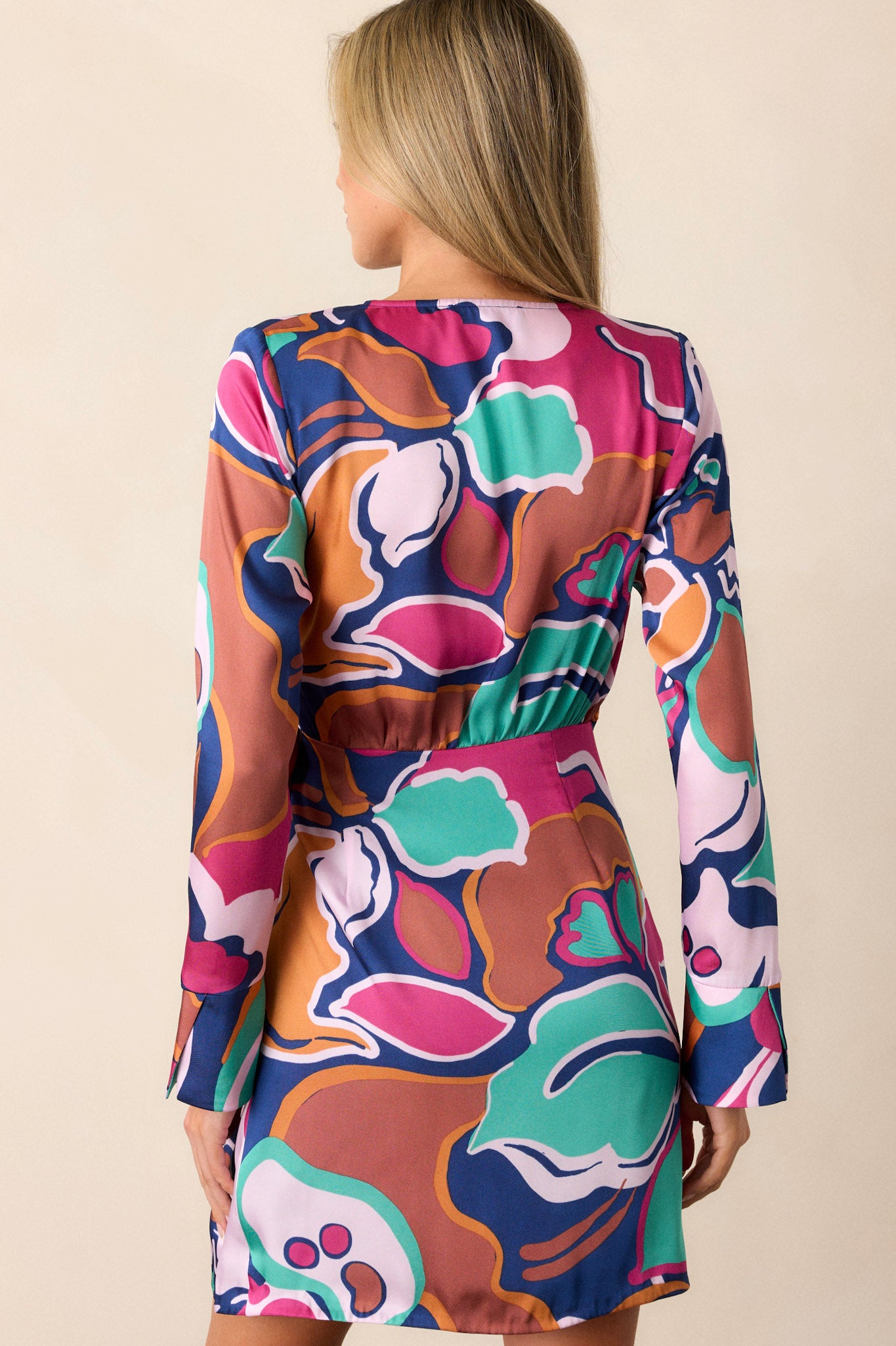 Back of this floral dress that features a v-neckline, long sleeves, a self-tie belt, and a fun floral print.