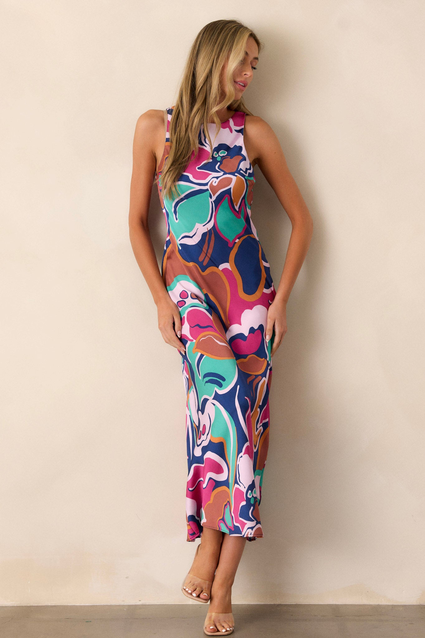 Side view of this midi dress that features a round neckline, a keyhole button closure, a unique abstract floral print, and a fun midi length.