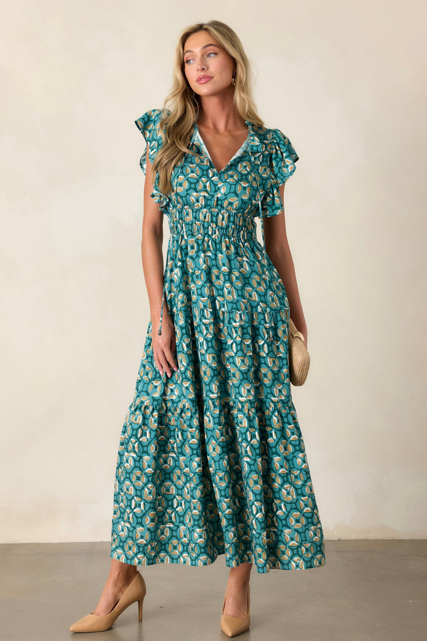 Front angled view of a green maxi dress featuring a ruffled v-neckline, self-tie drawstring neckline, elastic waistbands, functional hip pockets, a tiered design, and short ruffle sleeves