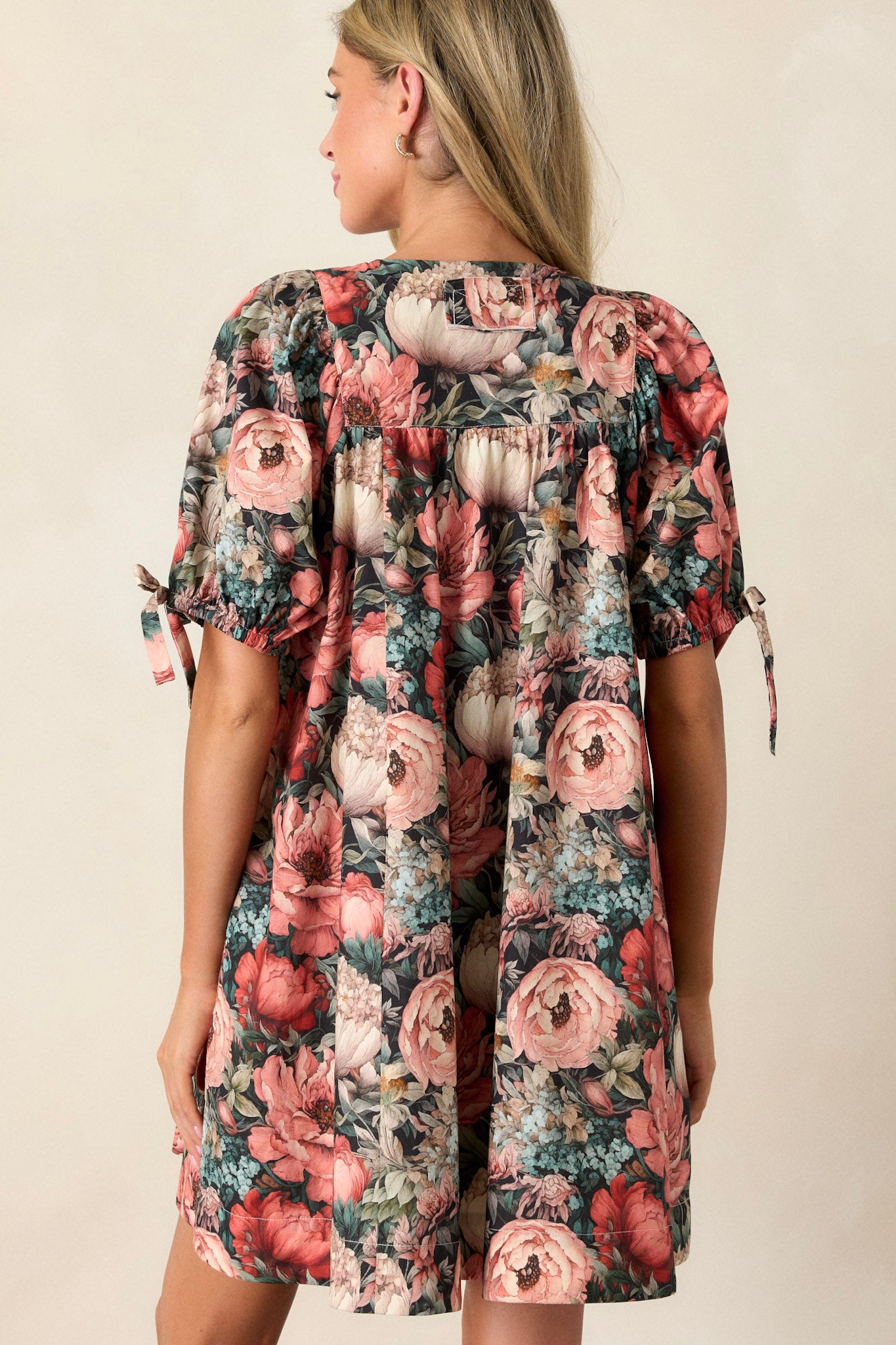 Back view of a black floral dress highlighting the puff sleeves, square neckline, and the fit of the dress from behind.