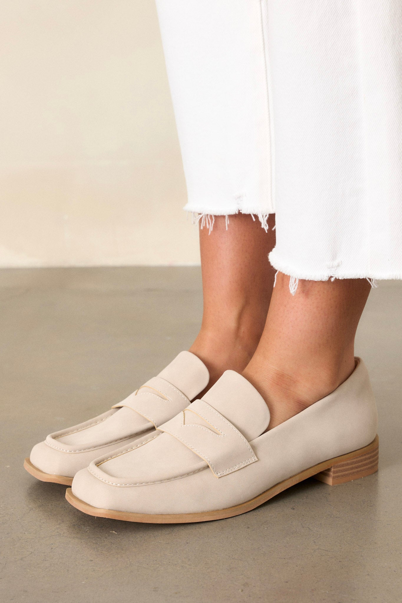 These taupe loafers feature a slip on design, a short block heel, a square toe, and decorative a saddle strap.