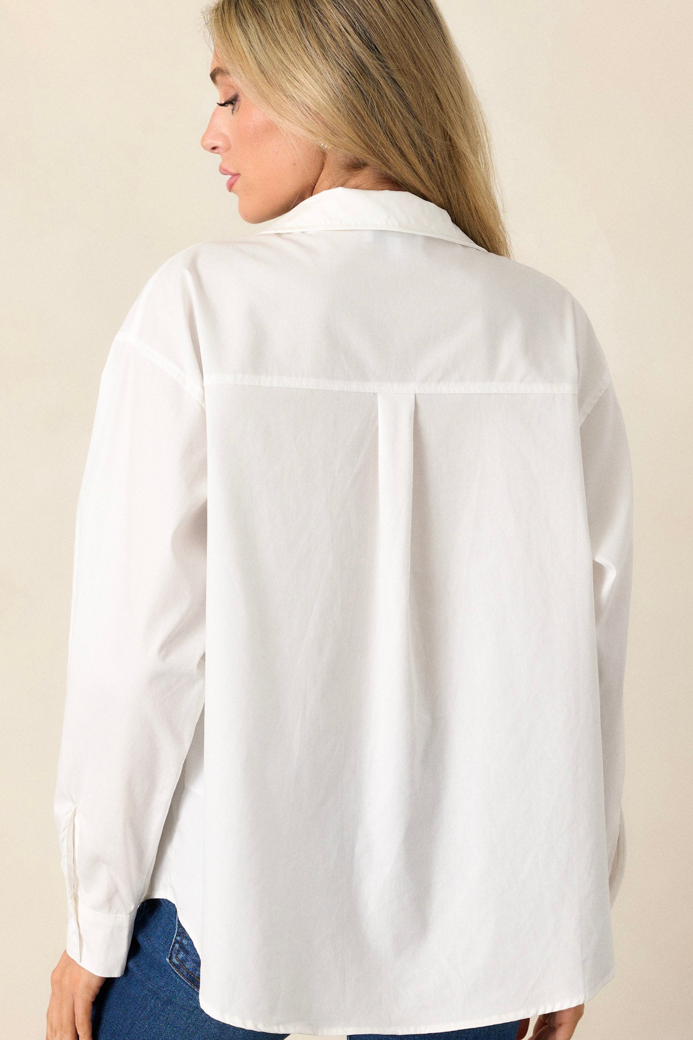 Back view of a white button-front top highlighting the relaxed fit, long sleeves, and overall back design.