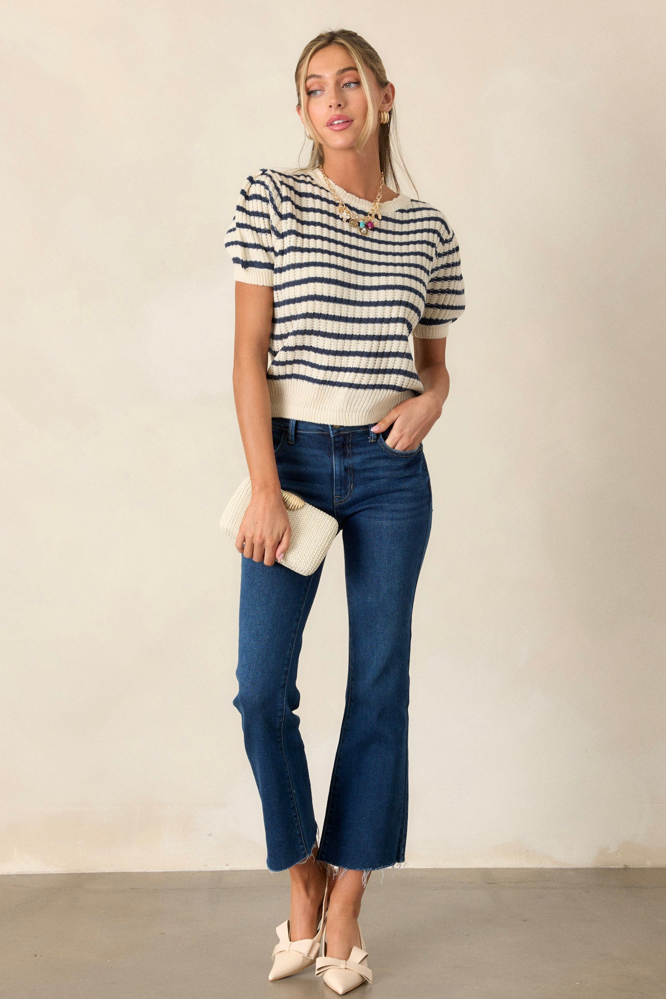 Front view of an ivory and navy striped top with a scalloped crew neckline, ribbed hems, short puff sleeves, and a slightly cropped fit.