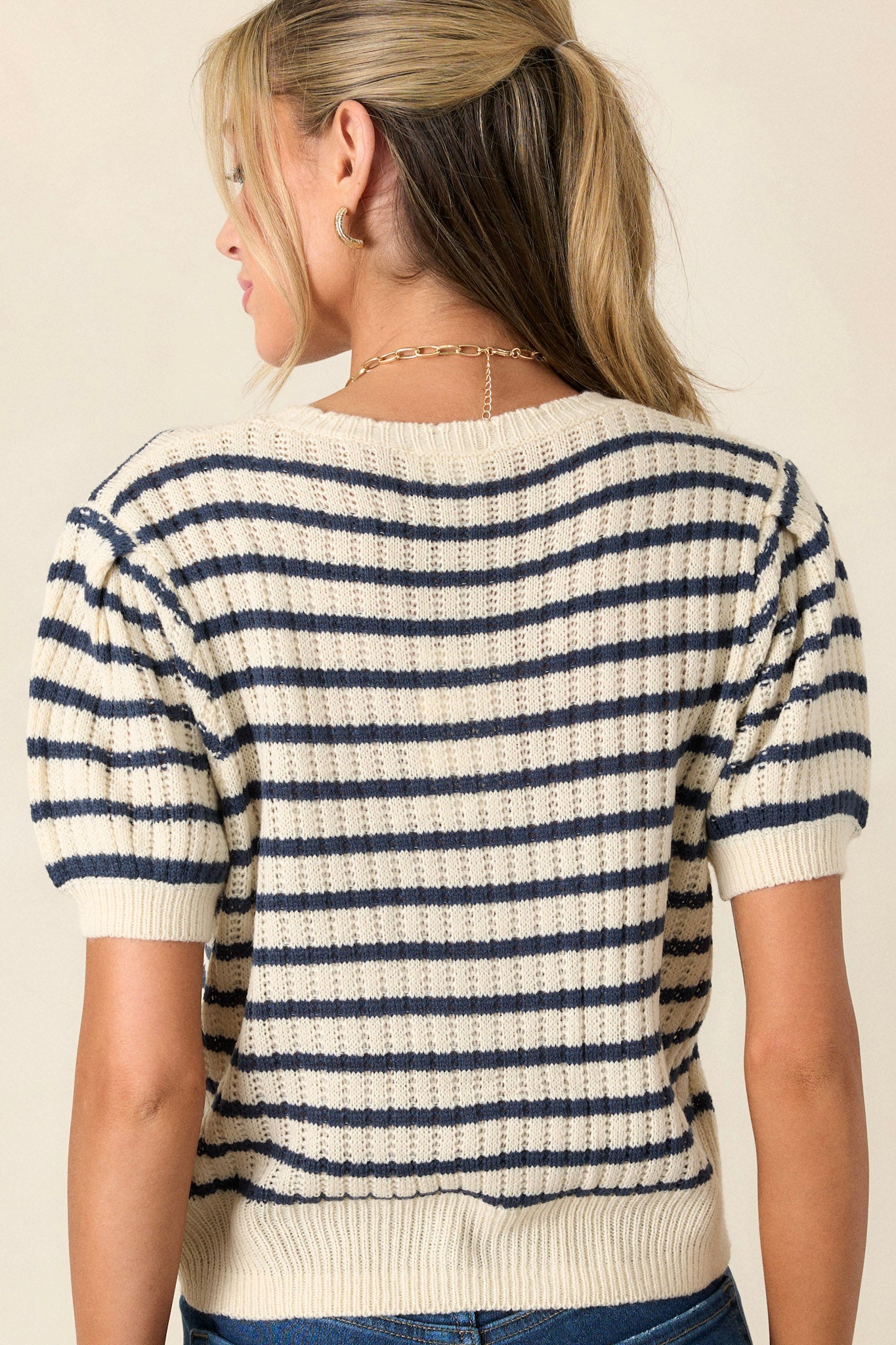 Back view of the ivory and navy striped top showcasing the scalloped crew neckline, knit fabric, and short puff sleeves.