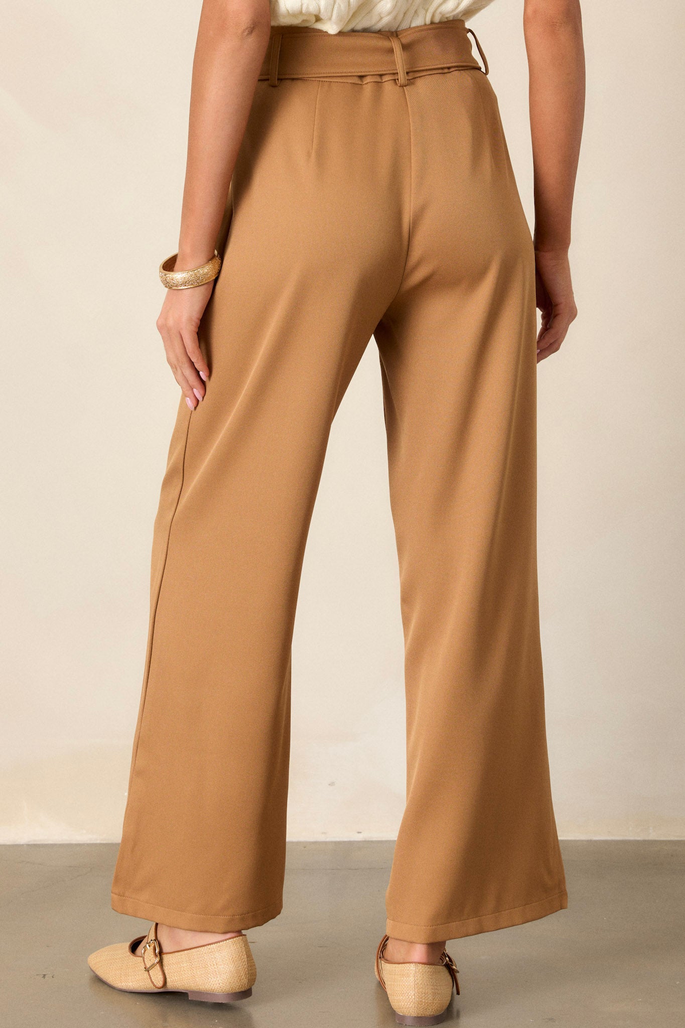 Back view of brown belted pants highlighting the high waist, the built-in adjustable cloth belt, and the wide leg design.