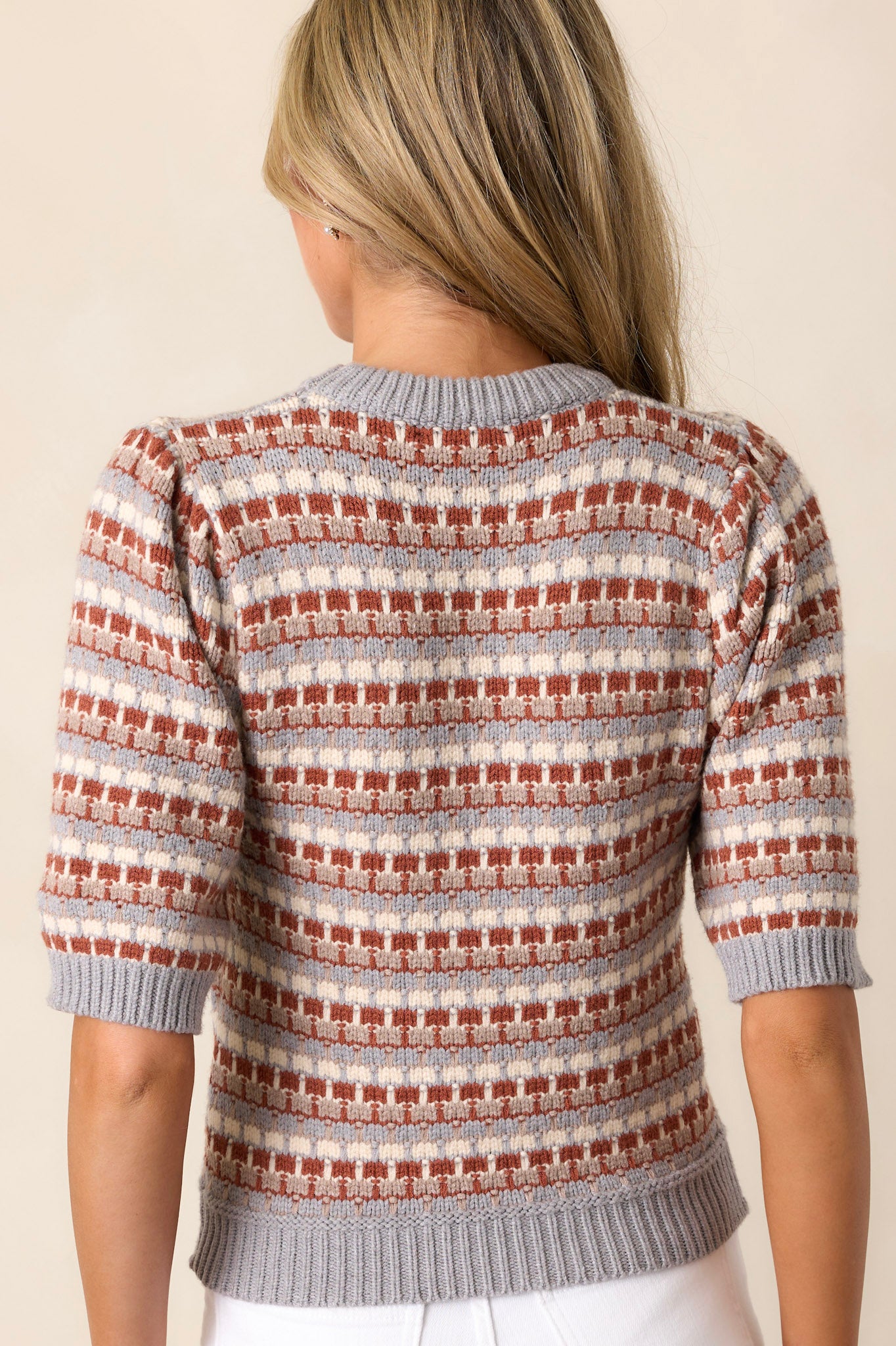 Back view of a grey stripe sweater highlighting the multi-color stripe design, soft knit texture, and the ribbed hemline.