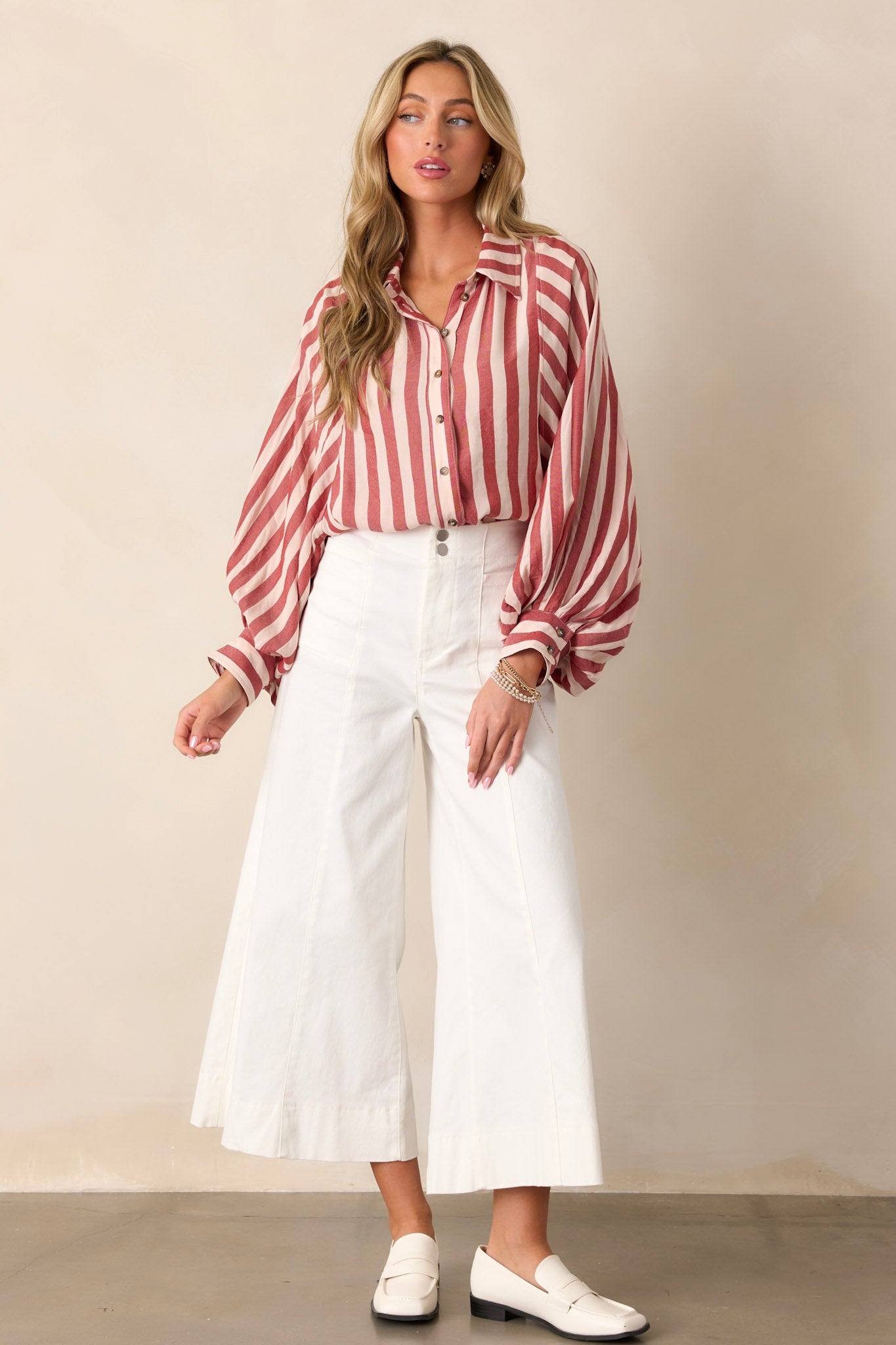 Full length view of white pants with a high waisted design, a double button closure with a zipper, functional front pockets, front & back seams, and a wide leg with a cropped length