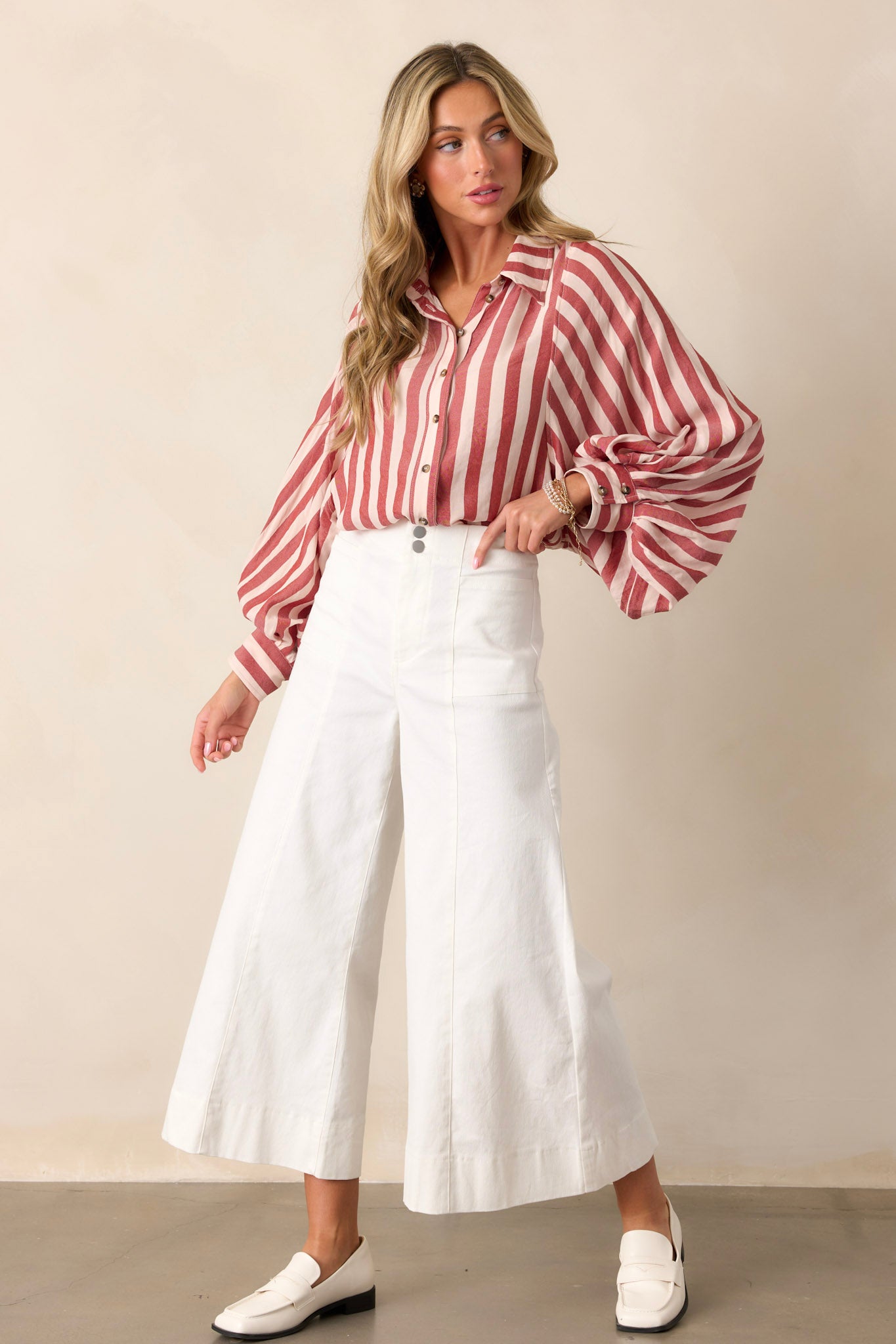 These white pants feature a high waisted design, a double button closure with a zipper, functional front pockets, front & back seams, and a wide leg with a cropped length.