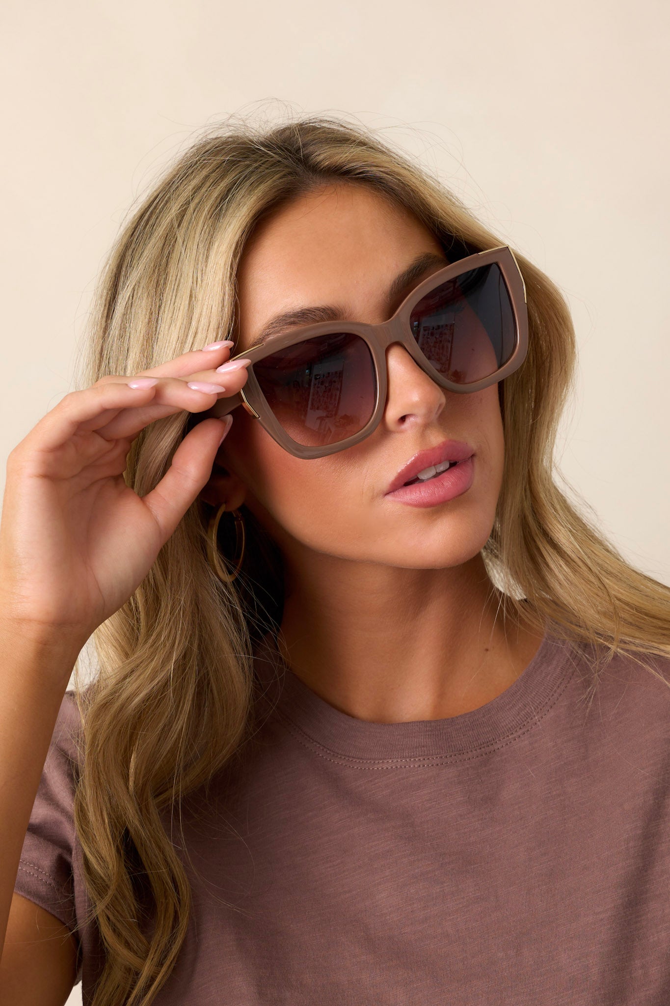 Close-up of these brown sunglasses that feature a cat-eye shape, a color fade lens, and gold detailing around the frame.