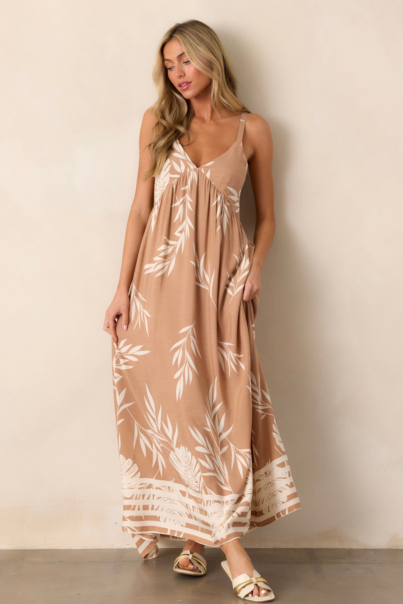 Action shot of the tan dress showcasing the flow and movement of the fabric, with emphasis on the v-neckline, smocked back, and stripe detailing along the bottom hem.