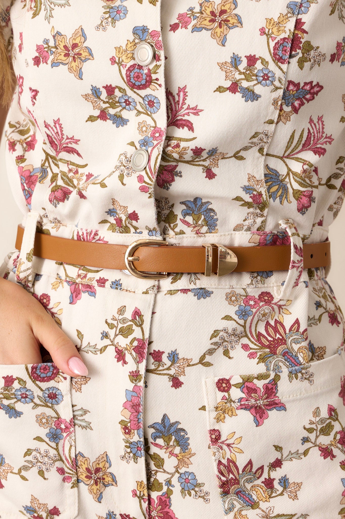 Close-up of this brown belt that features a small gold buckle closure, a smooth exterior and gold hardware.