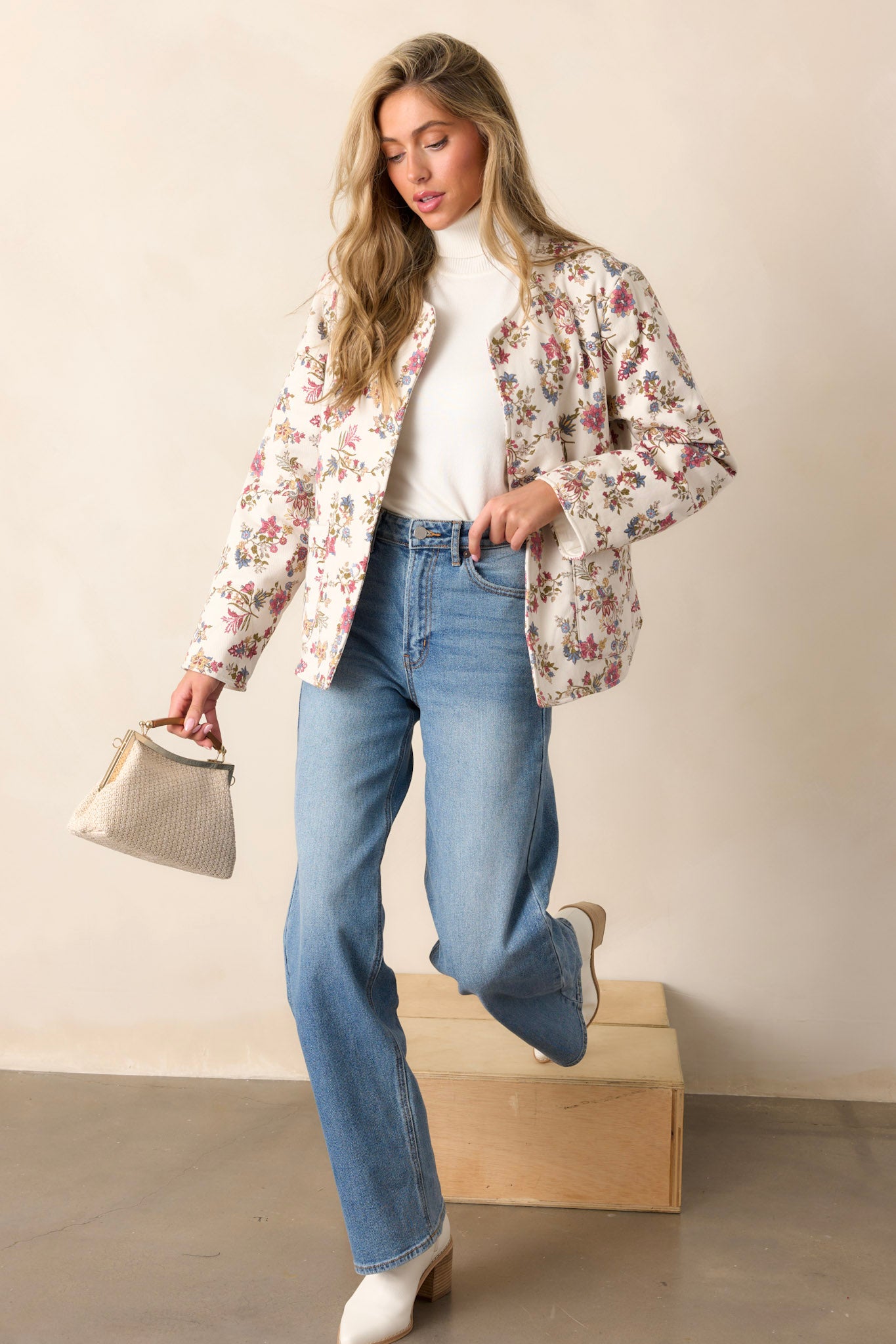 Action shot of an ivory floral jacket displaying the fit and movement of the floral denim fabric, highlighting the crew neckline, functional buttons, and hip pockets.