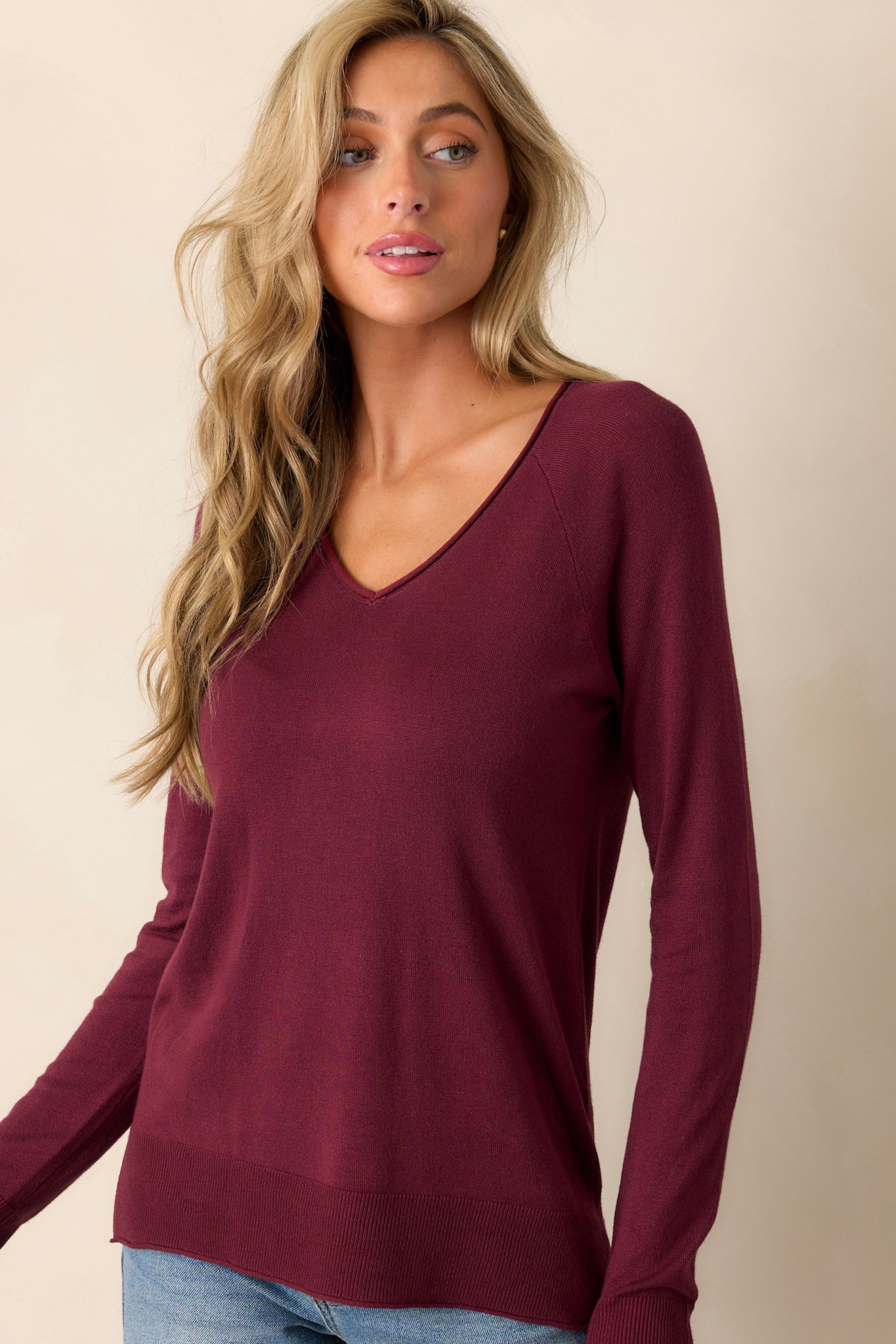 Focused view of the cuffed sleeve detail on a soft knit top with a raw-edged v-neckline.