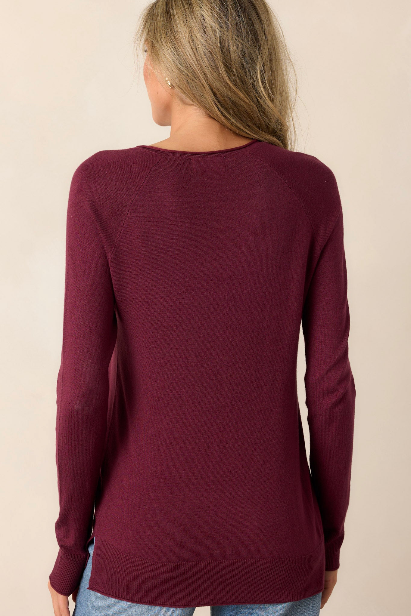 Back view of knit top, showing soft material and relaxed fit with long, cuffed sleeves.