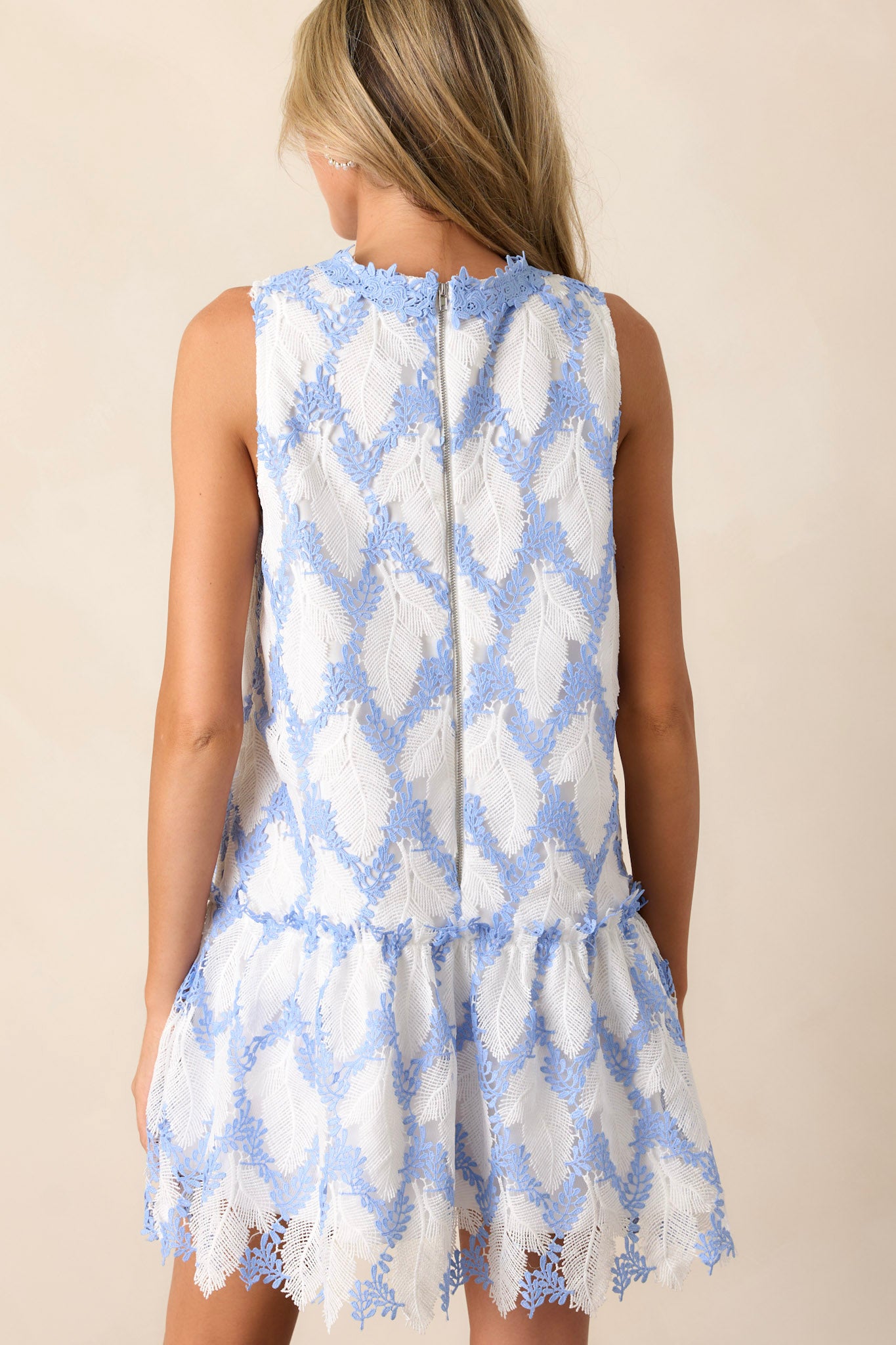 Back view of the blue dress highlighting the smooth finish and structure of the lace overlay, along with the sleeveless design and high crew neckline