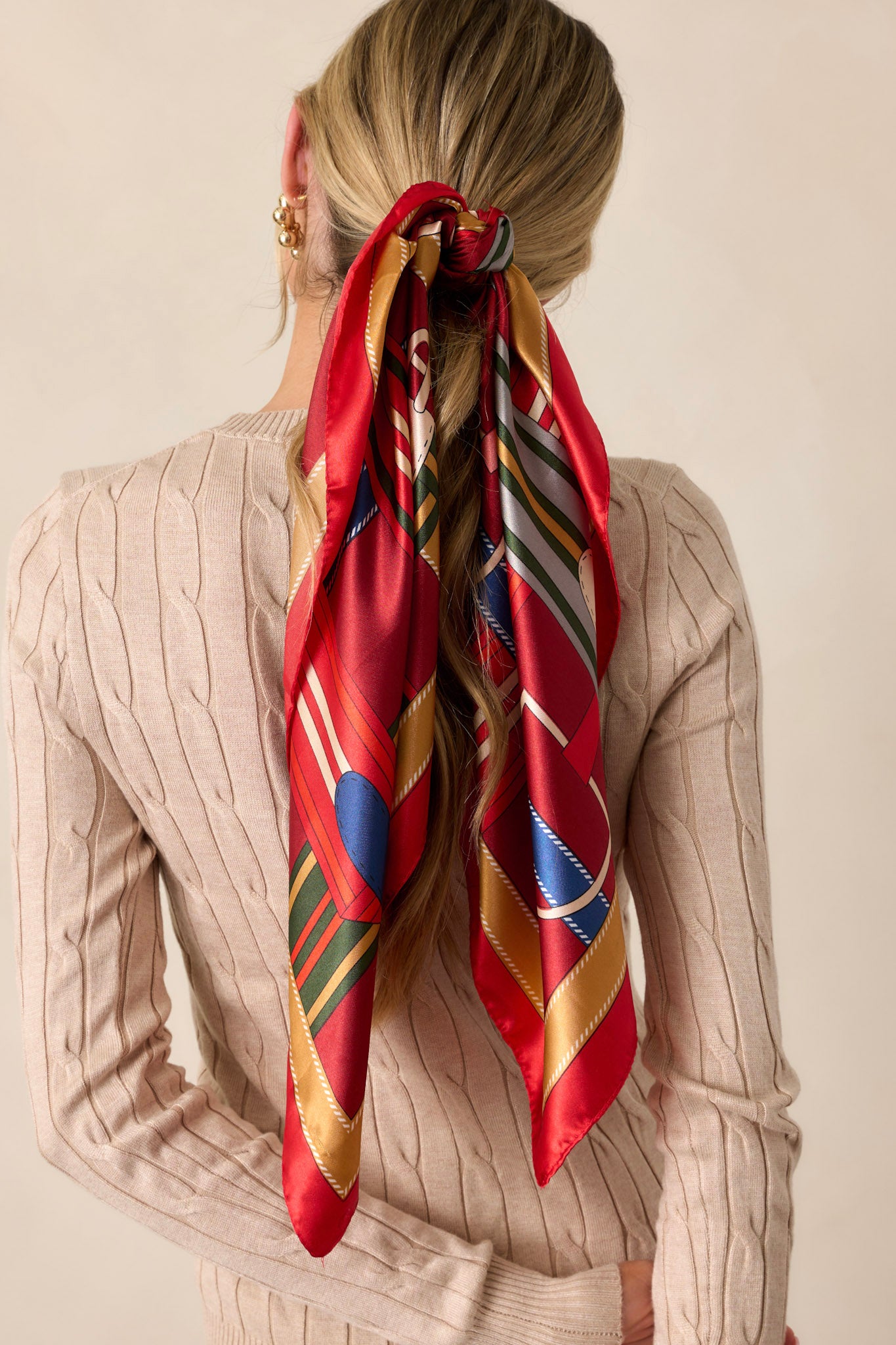 This red scarf features a satin material, and a multicolored print.