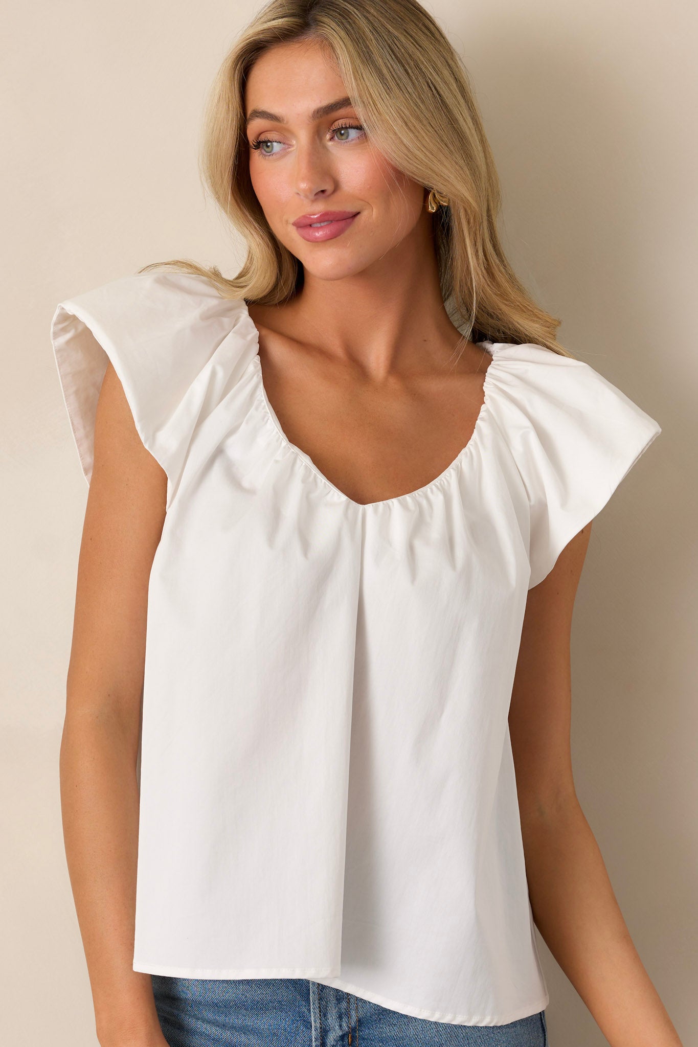 Front angled view of a white top featuring a v-neckline, flutter sleeves, a casual fit, and a flowy design