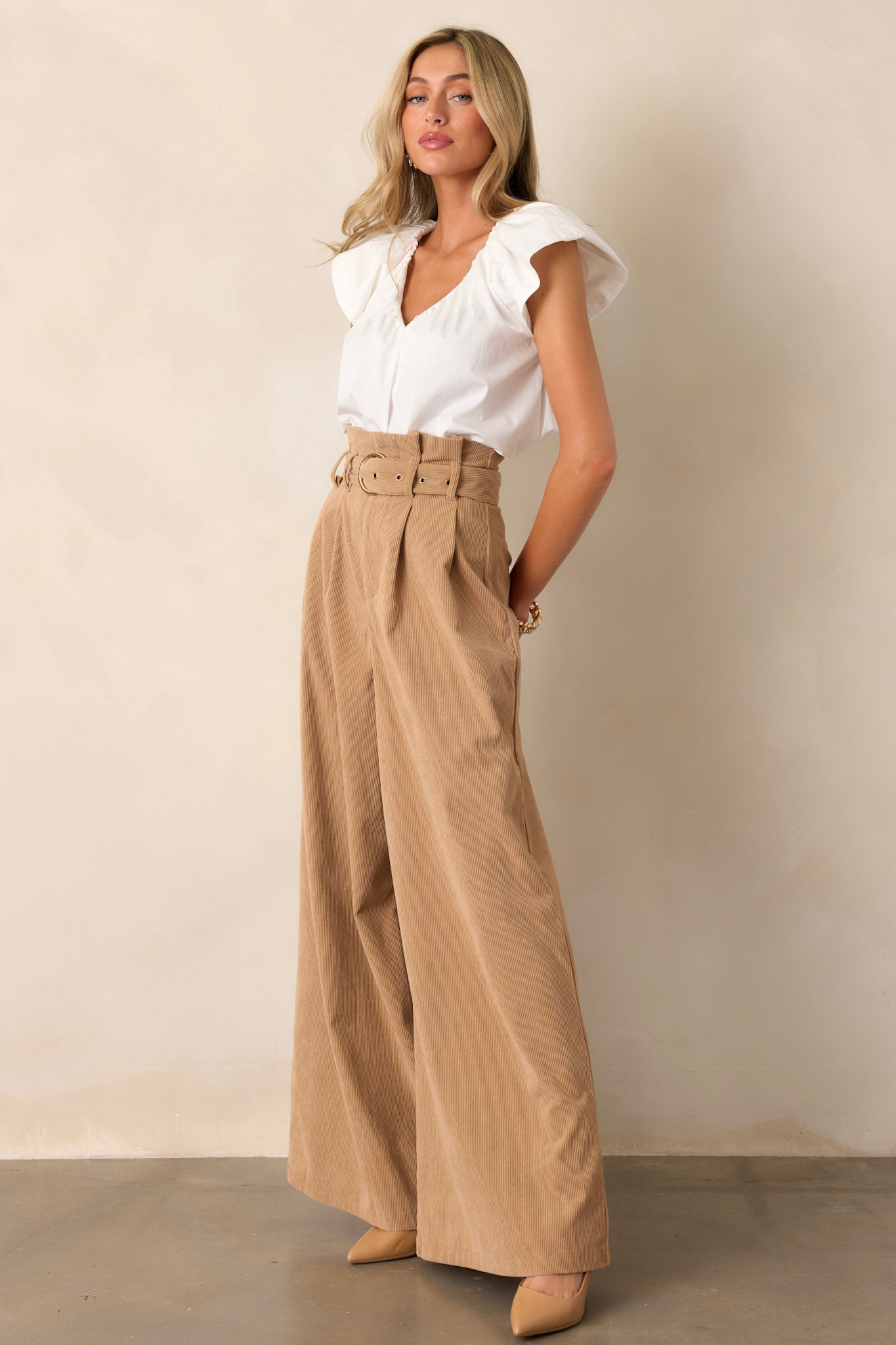 Side view of tan pants showcasing the paper bag waistline with the adjustable belt and the flowing leg design, emphasizing the relaxed fit.