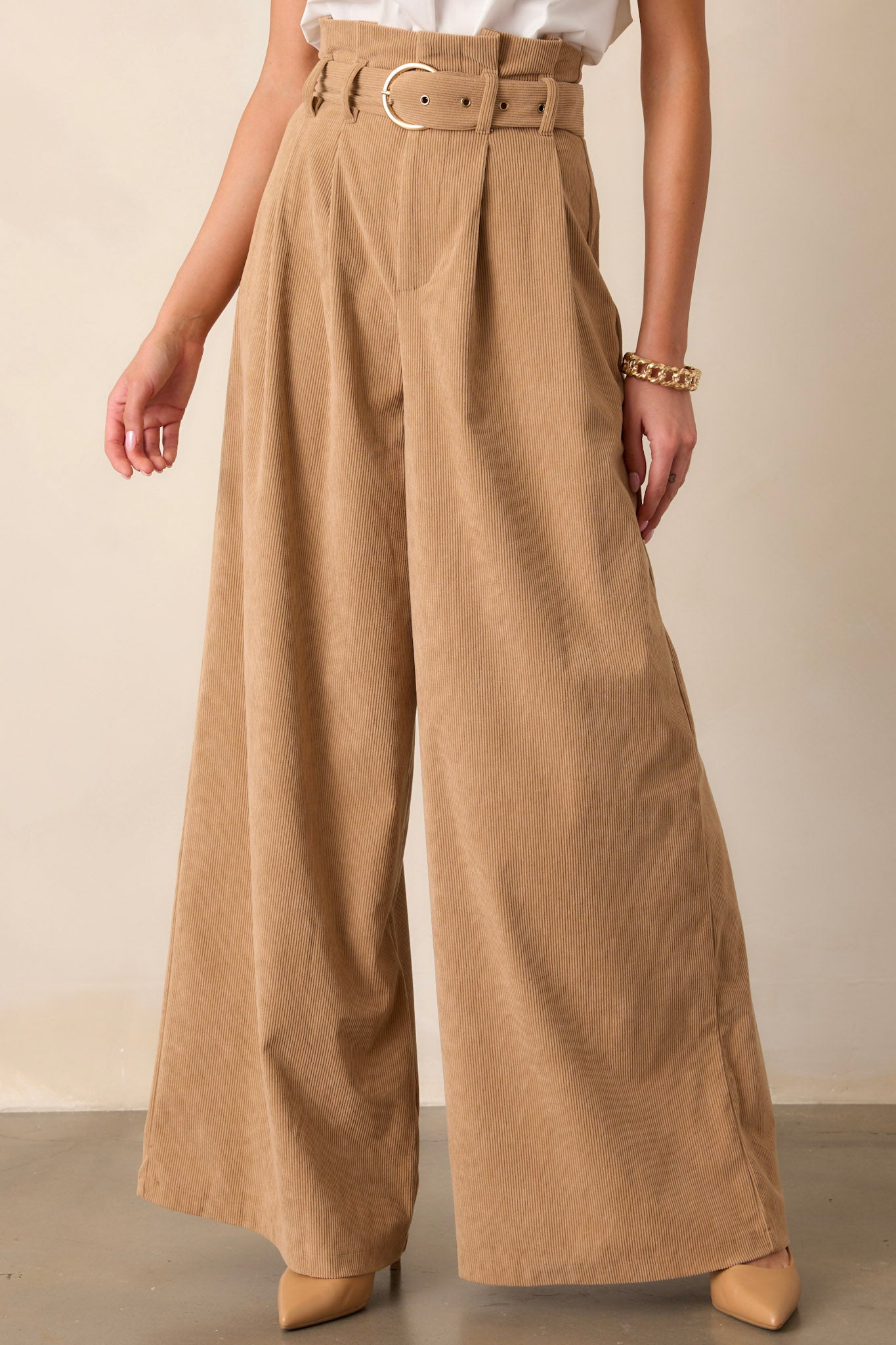 Wide-leg tan pants with a paper bag waist and belted detail, showcasing the loose, flowing silhouette from waist to hem.