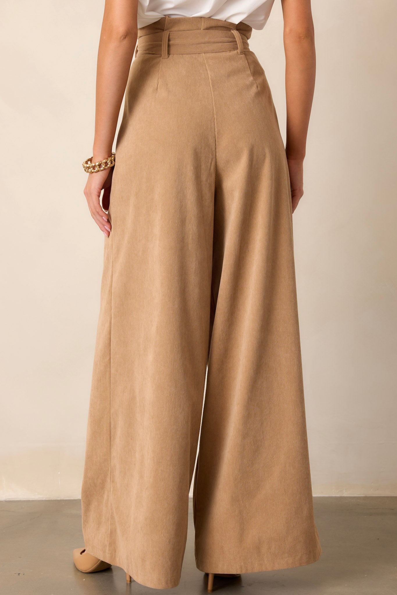 Back view of tan pants highlighting the paper bag waistline, the adjustable belt, and the flowy leg design.