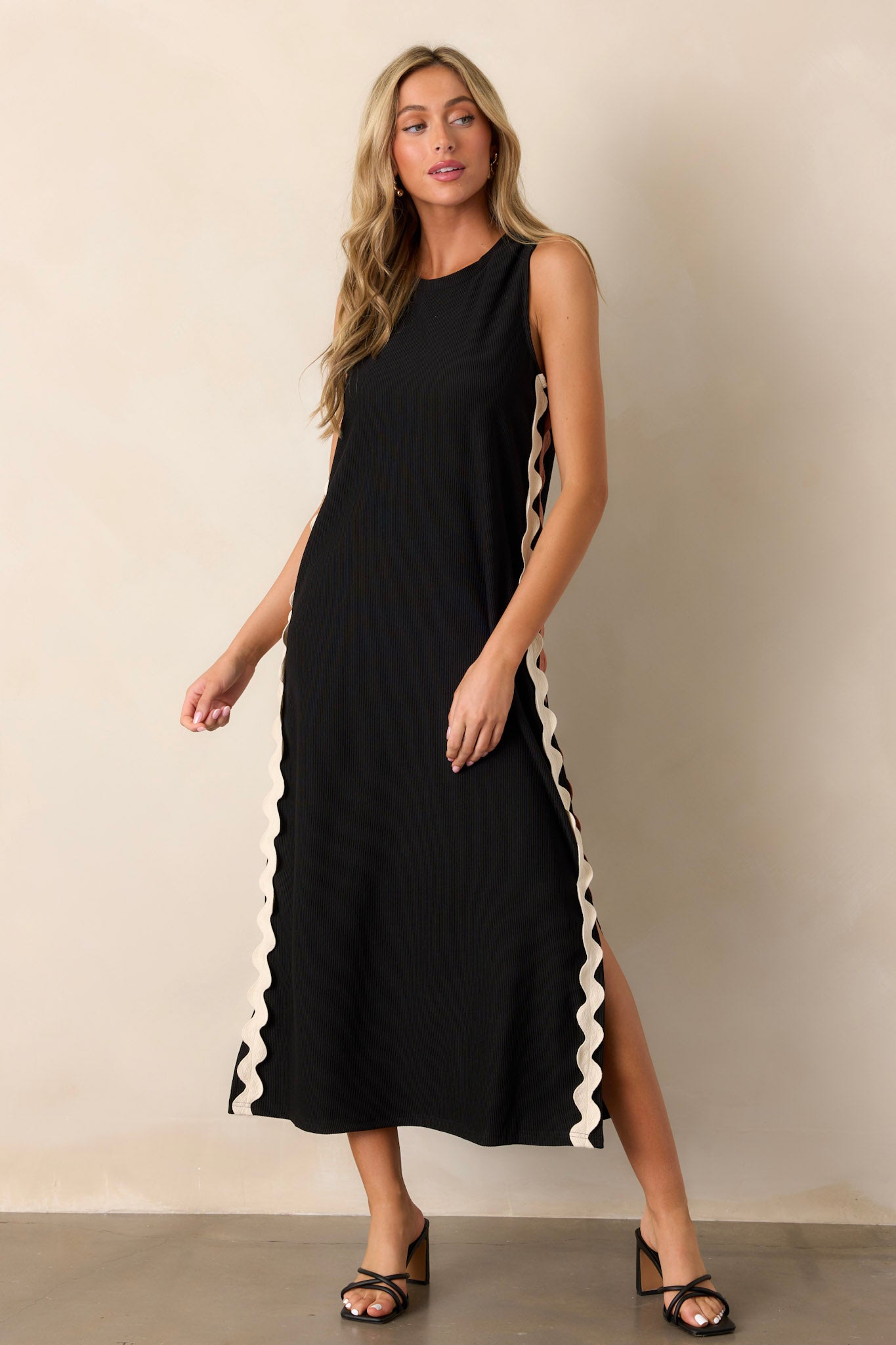 Action shot of the black midi dress displaying the flow and movement of the side slits, highlighting the ribbed material and two-toned ricrac side detailing.