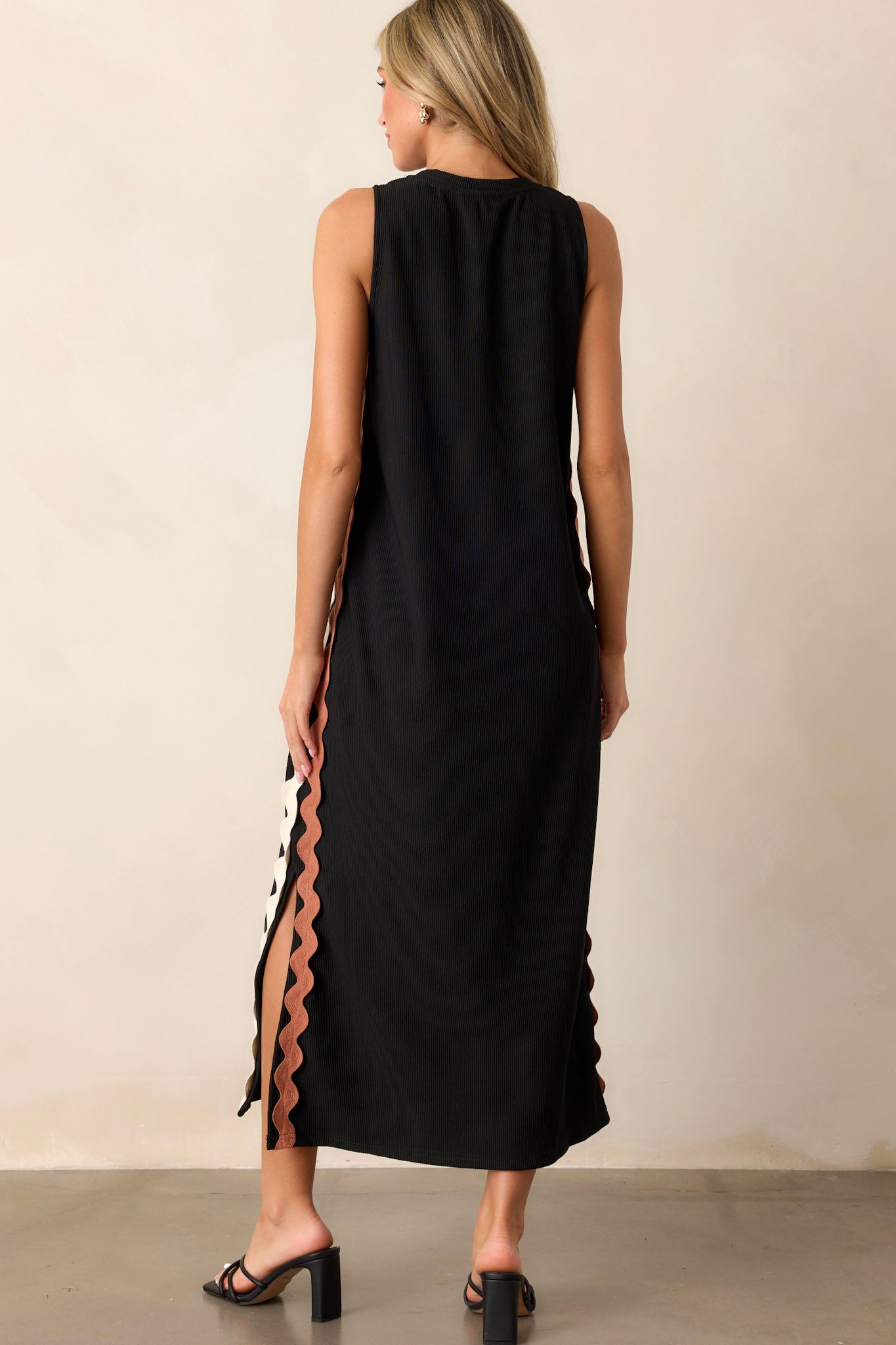 Back view of the black midi dress highlighting the ribbed material, side slits, and the sleek silhouette of the sleeveless design.