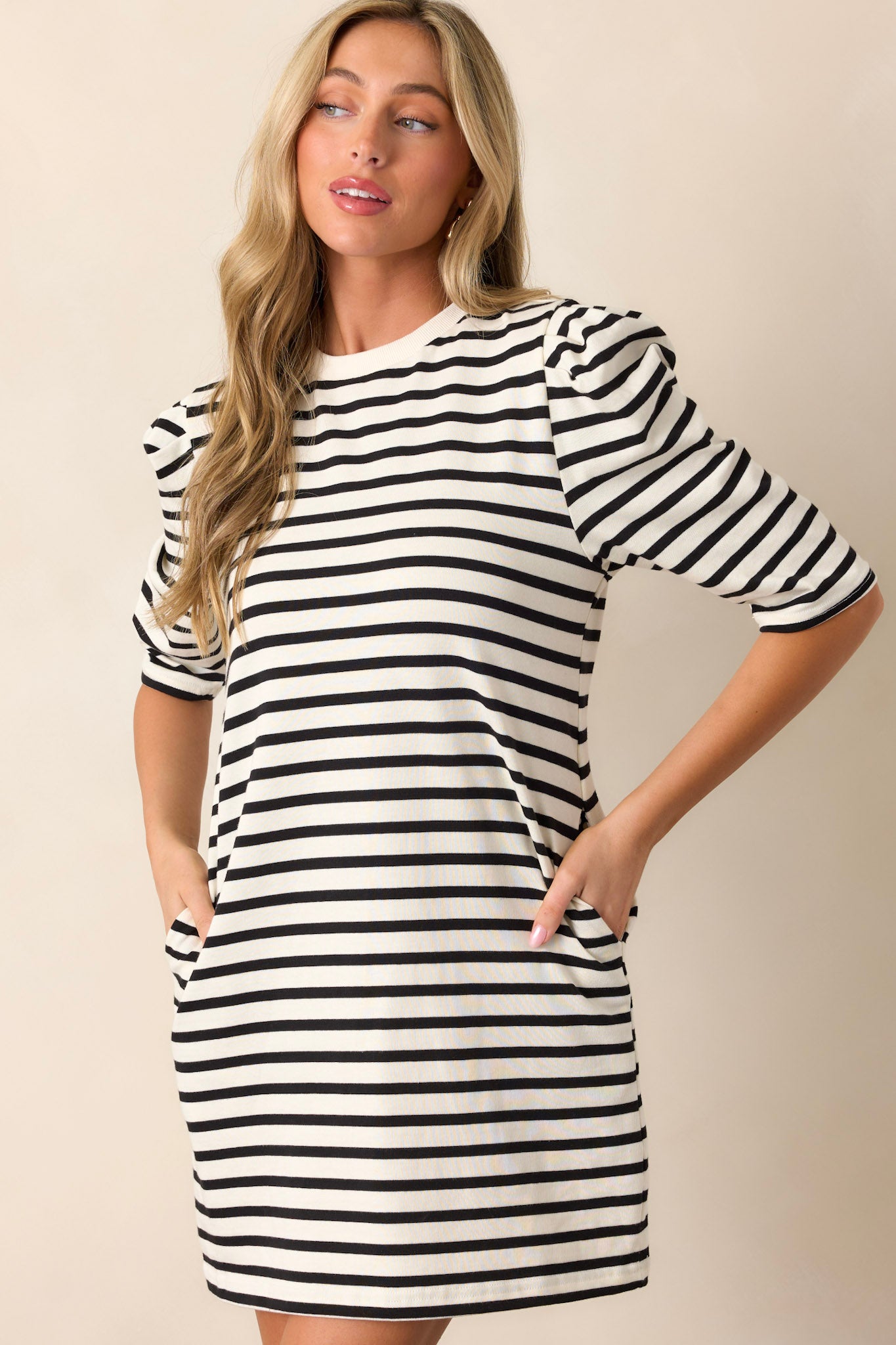 Front view of a white dress featuring a crew neckline, long puff sleeves, functional hip pockets, and a relaxed fit.