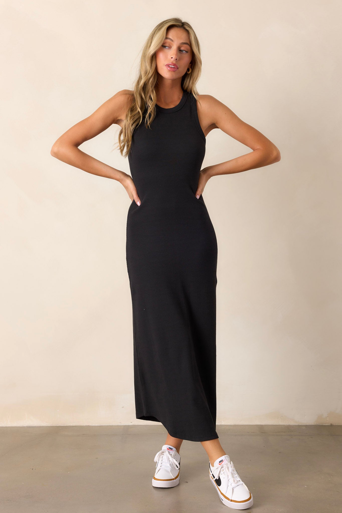 This black dress features a ribbed fabric, scoop hem, and a bodycon design.