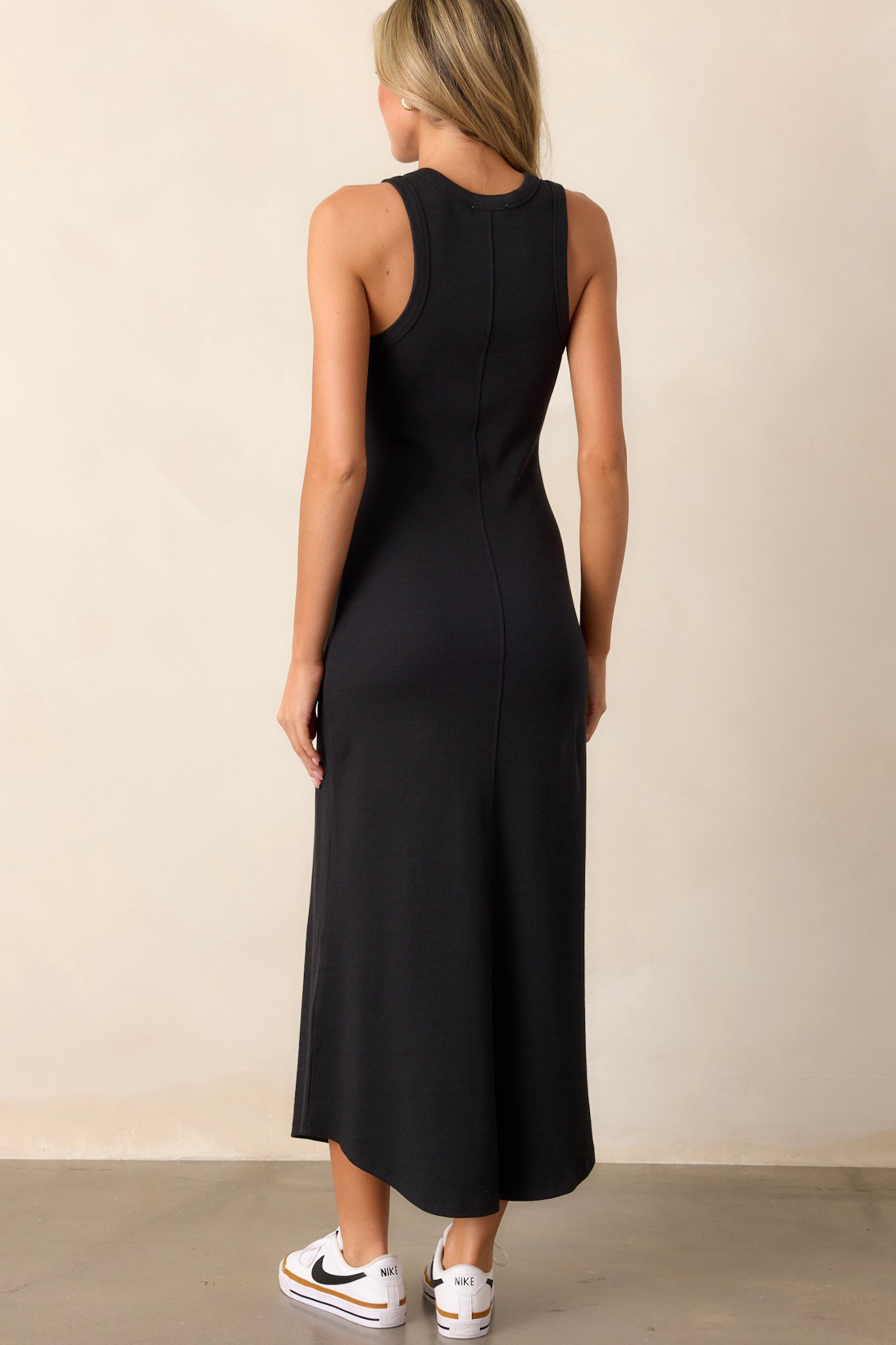 Back view of the black dress highlighting the smooth, continuous ribbed fabric and the flattering bodycon fit.