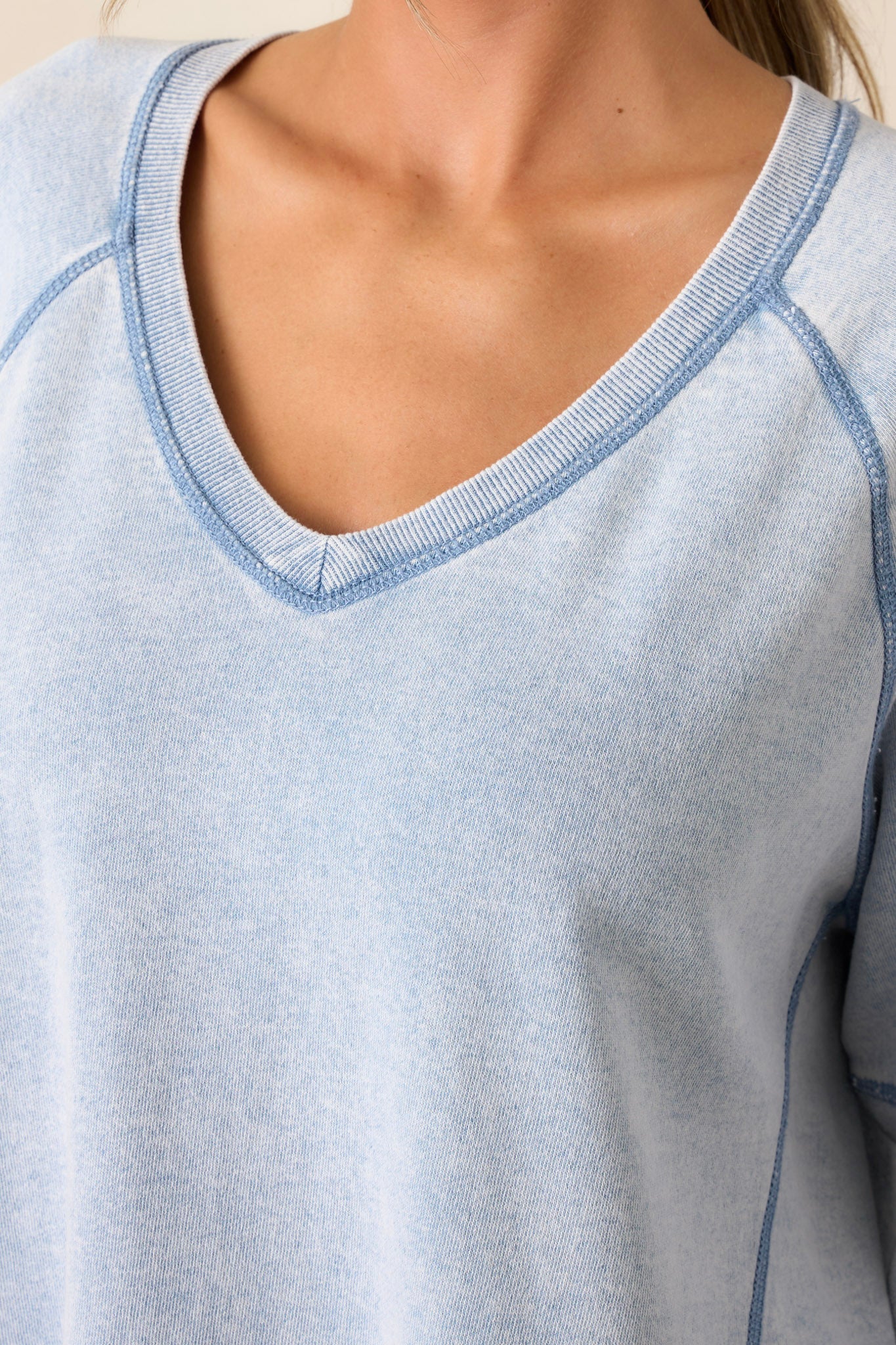 Close-up of the indigo sweatshirt focusing on the v-neckline, soft knit texture, and one of the side slits in the hemline.