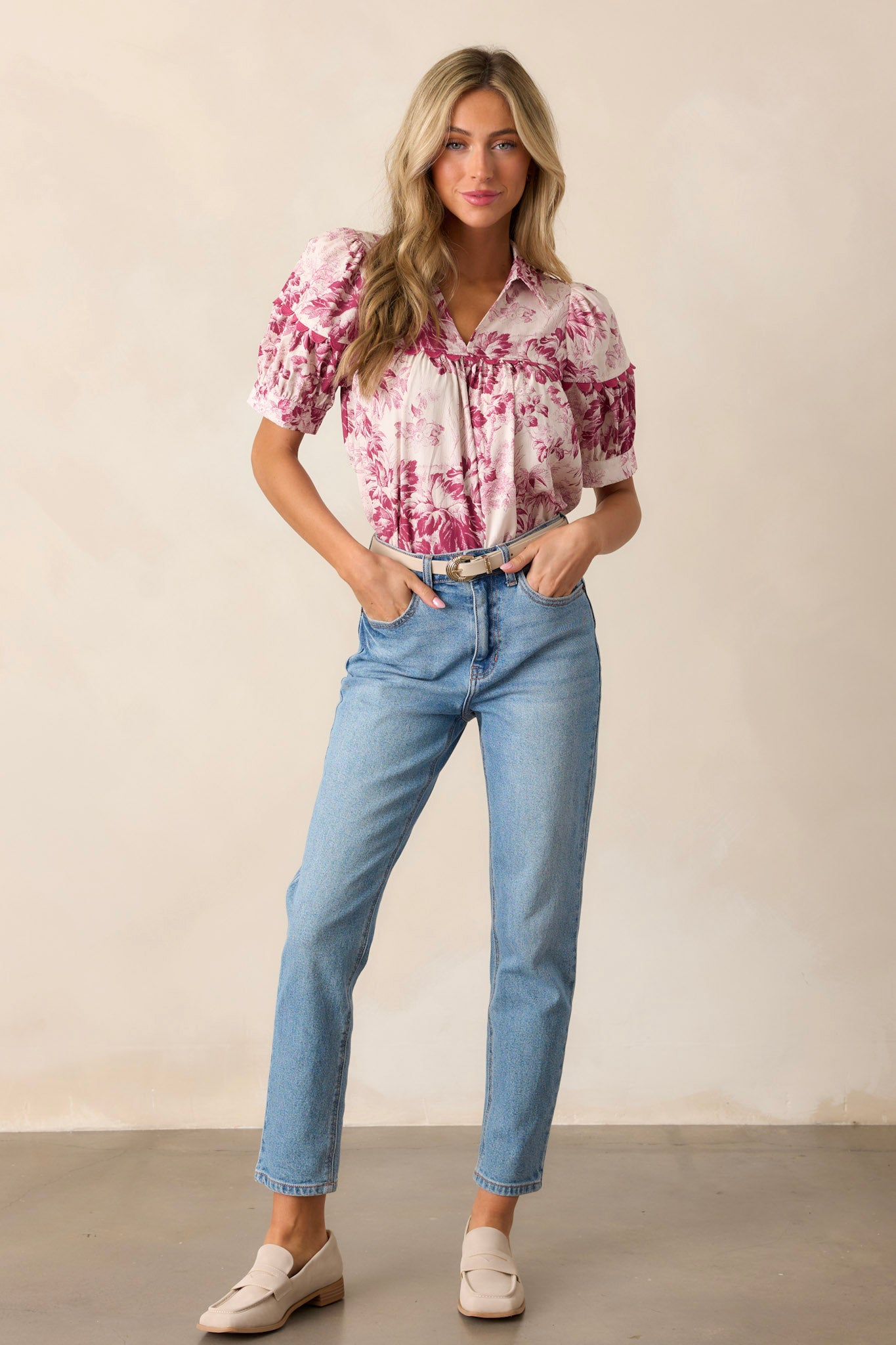 Front view of a magenta top featuring a collared v-neckline, scallop detailing across the bust, puff sleeves, and a floral design.