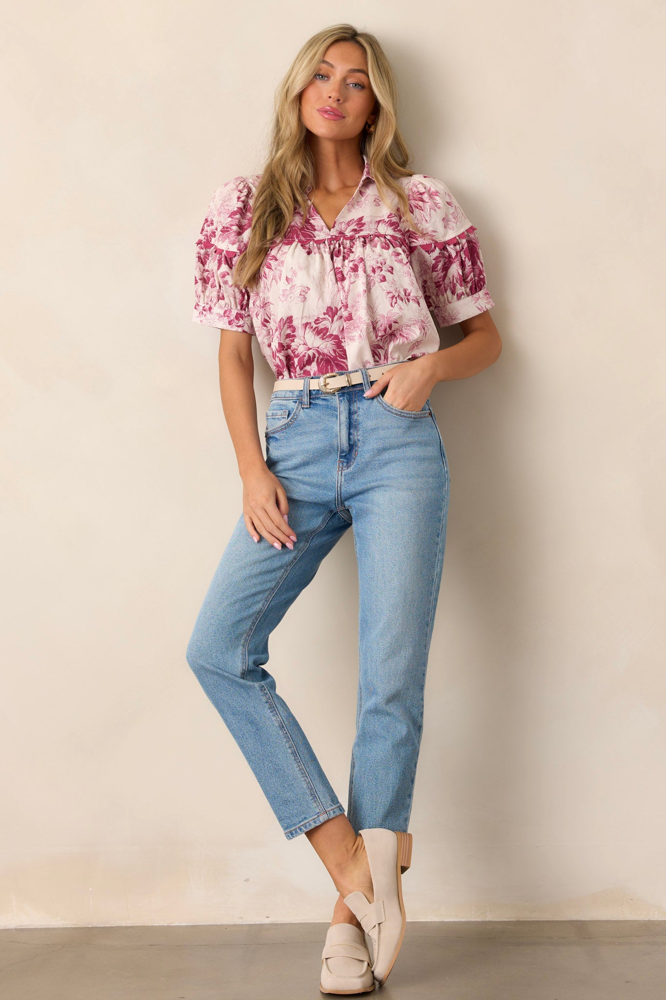 A magenta top with a collared v-neckline, scallop design across the bust, pleated detailing, puff sleeves, and a floral pattern, shown from the front.