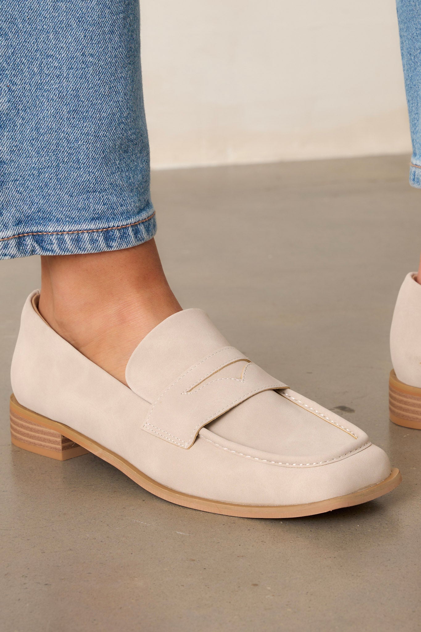 Close up view of these taupe loafers that feature a slip on design, a short block heel, a square toe, and decorative a saddle strap.&nbsp;