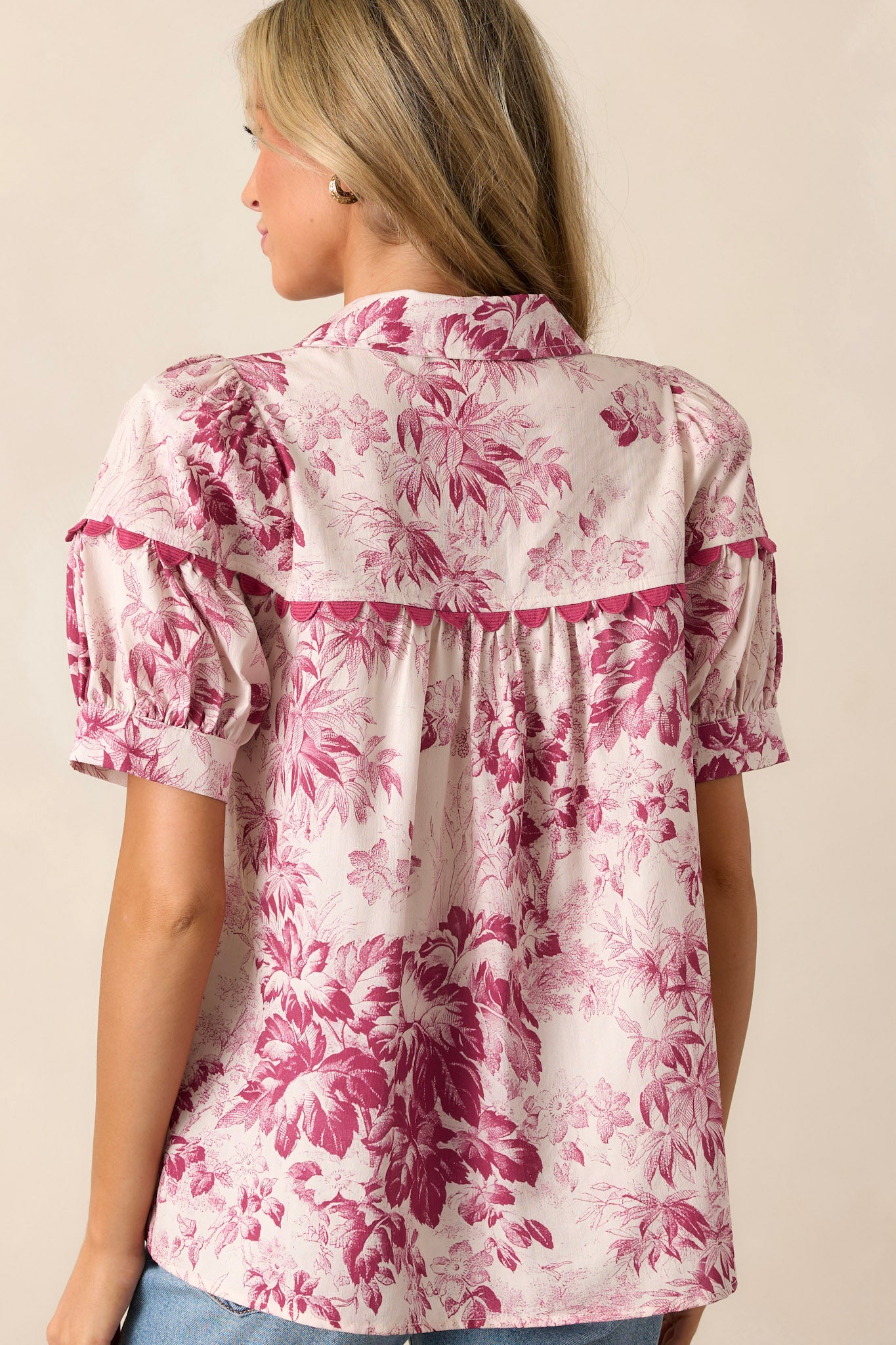 Back view of the magenta top displaying the floral pattern, puff sleeves, and pleated detailing.