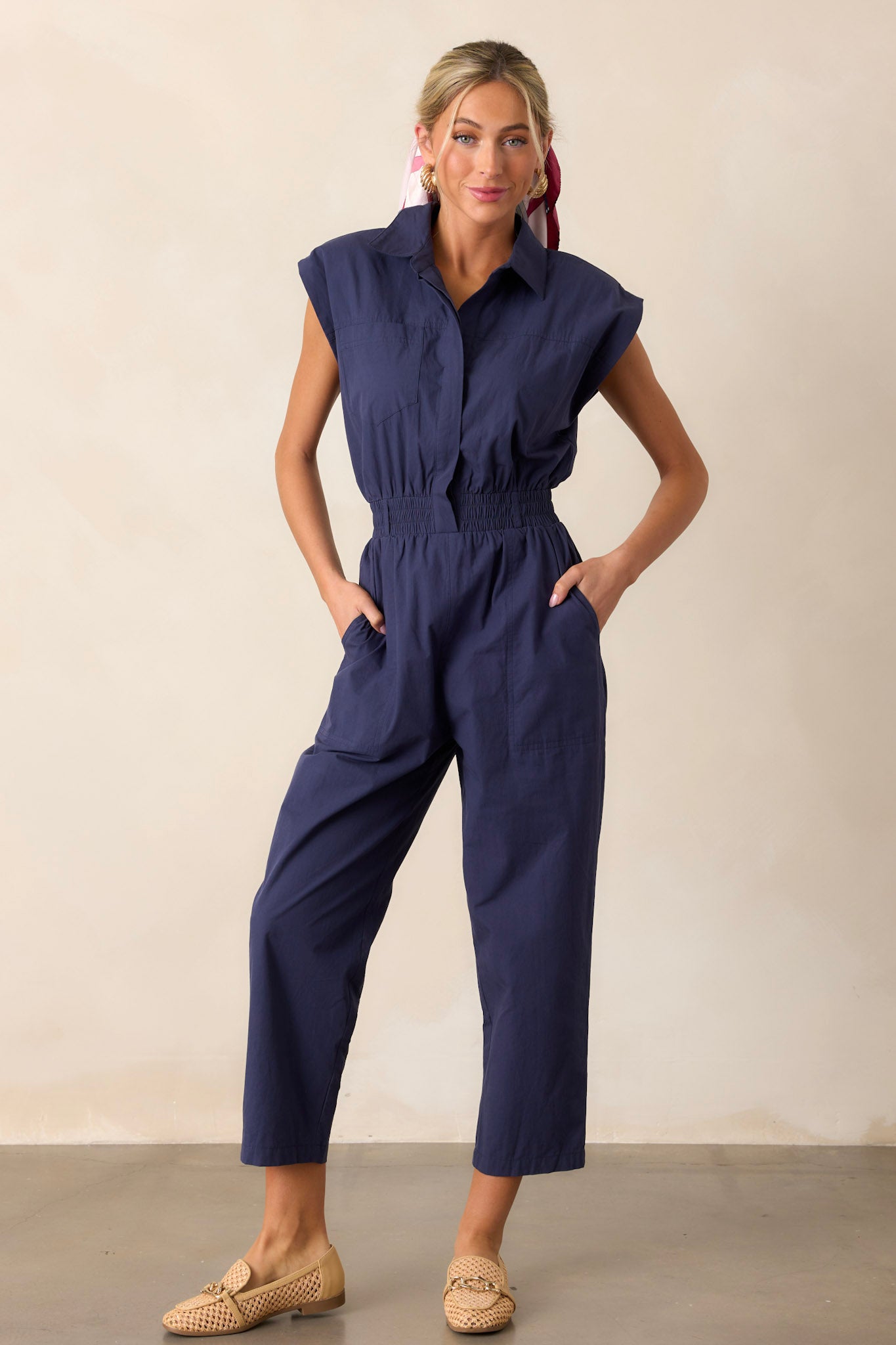 Full length view of a jumpsuit featuring a popped collar, two side pockets, and a stretchy soft waistband