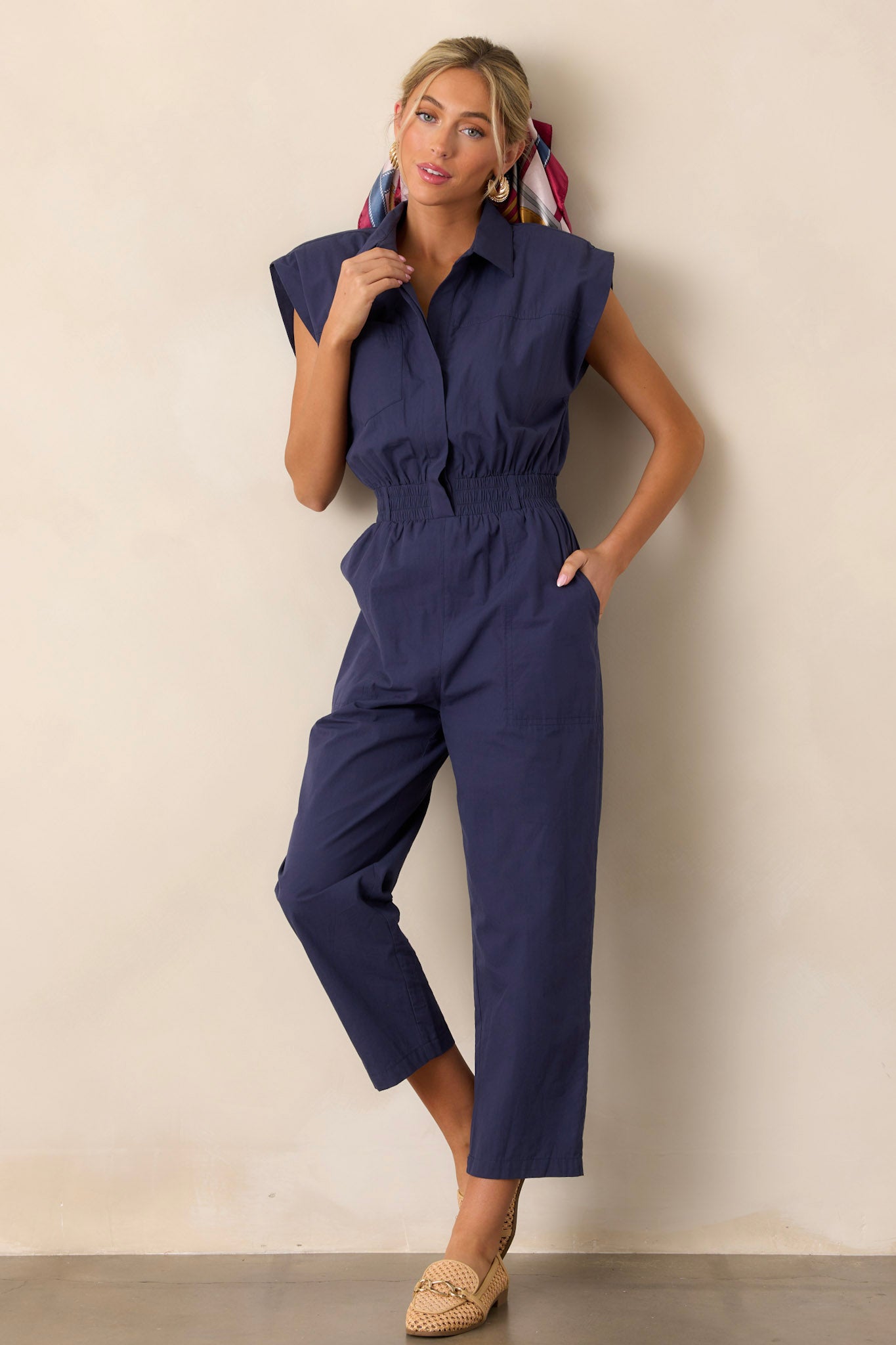 Front view of a jumpsuit featuring a popped collar, two side pockets, and a stretchy soft waistband.