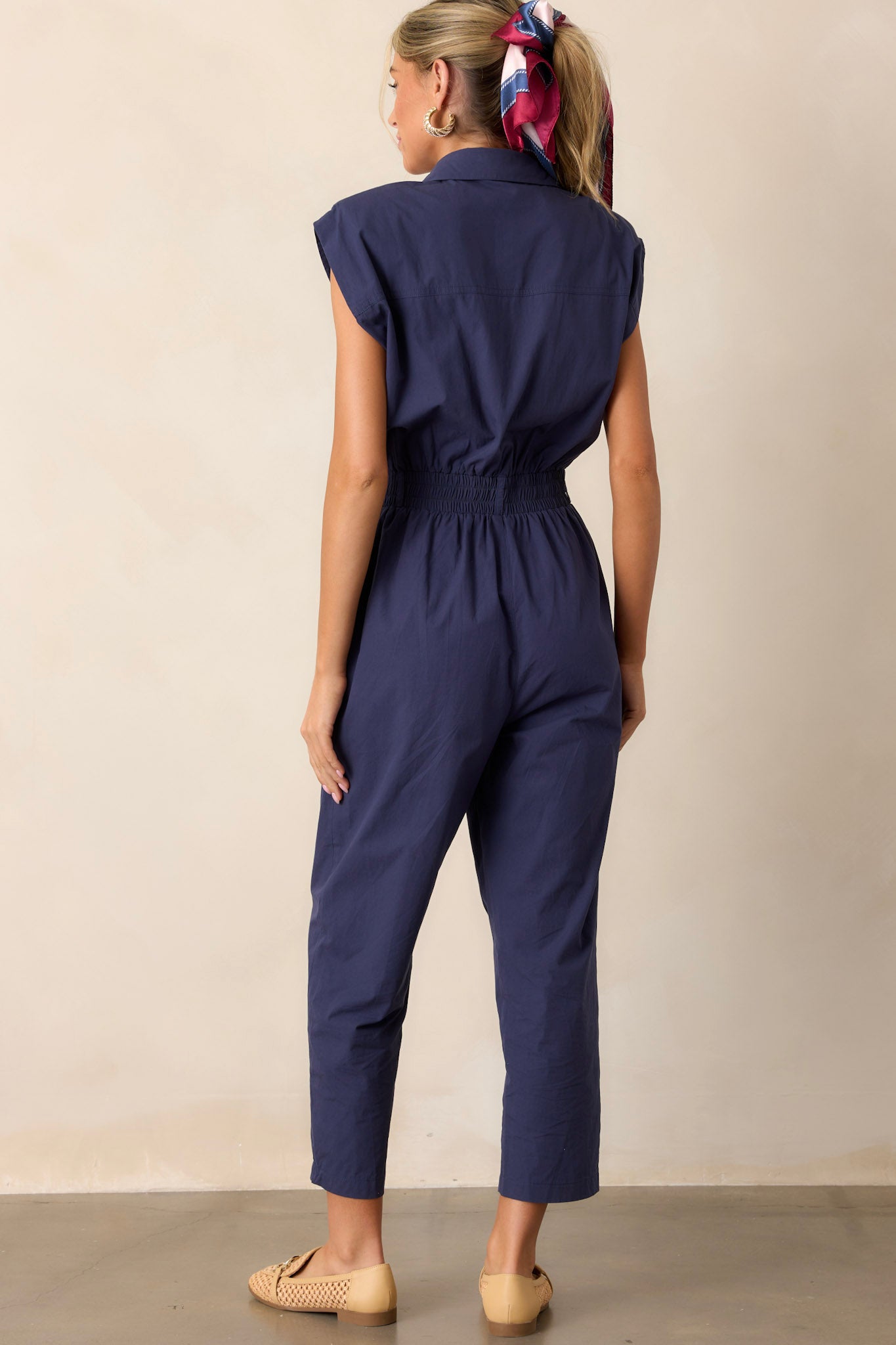 Back view of the jumpsuit highlighting the smooth, fitted appearance of the stretchy waistband and the relaxed fit below