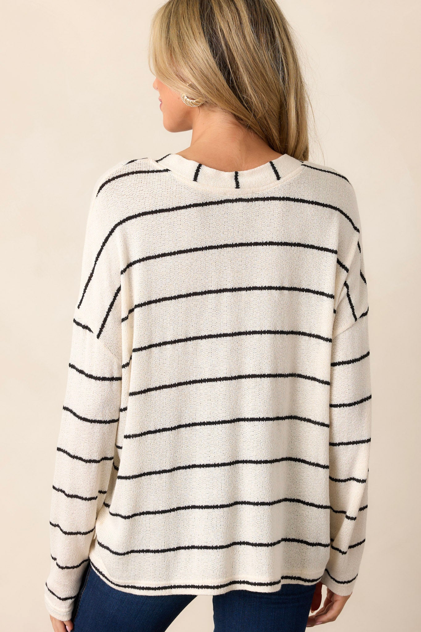 Back view of the sweater highlighting the horizontal stripe pattern and the breathable knit fabric, with long sleeves extending to the wrists.