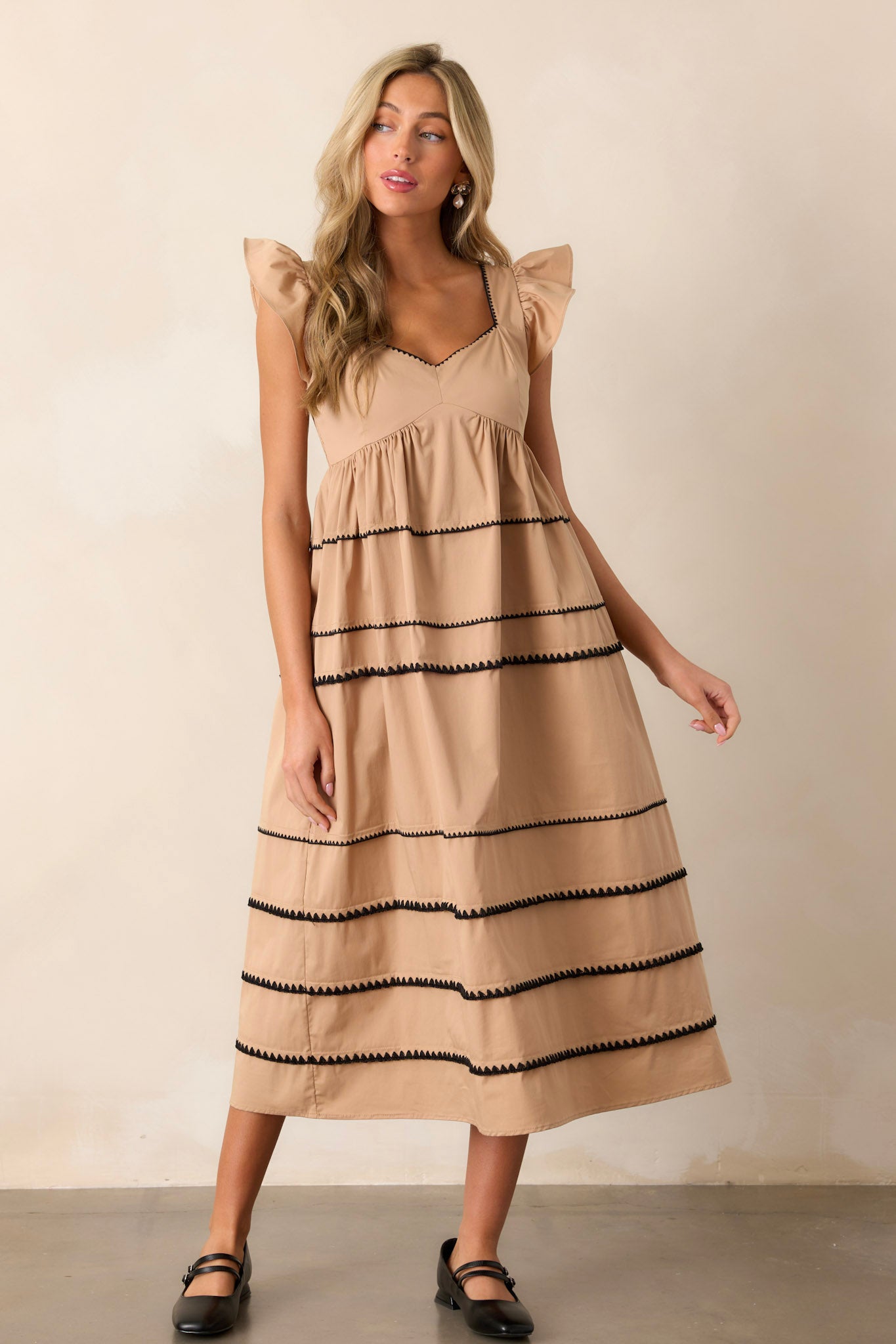 Action shot of the tan dress displaying the flow and movement of the fabric, highlighting the ruffle cap sleeves, multiple tiers, and the ric-rac detailing.