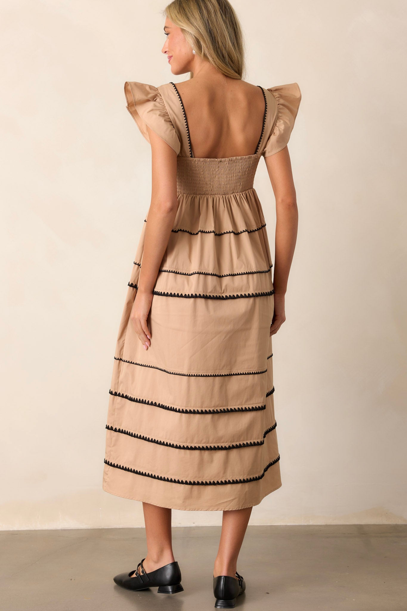 Back view of the tan dress highlighting the smocked back, the multiple tiers, and the ric-rac detailing.