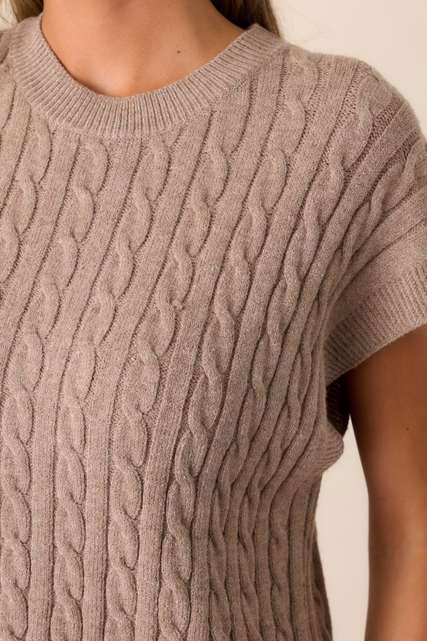 Close-up of the taupe top focusing on the intricate cable-knit pattern, the ribbed neckline, and the texture of the short cap sleeves.