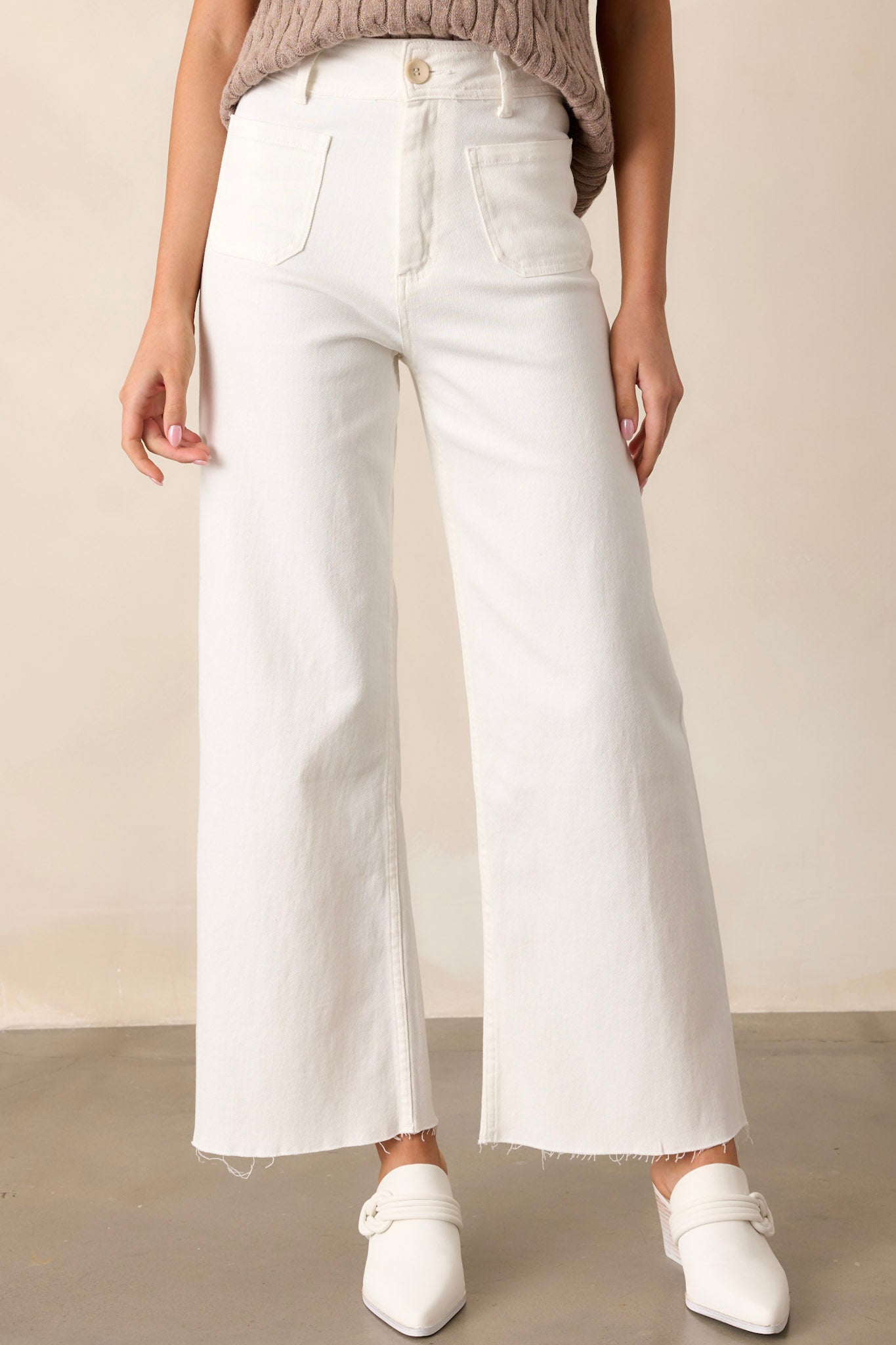 These ivory pants feature a high waisted design, a button & zipper closure, belt loops, functional front & back pockets, a wide leg design, and a raw hemline.