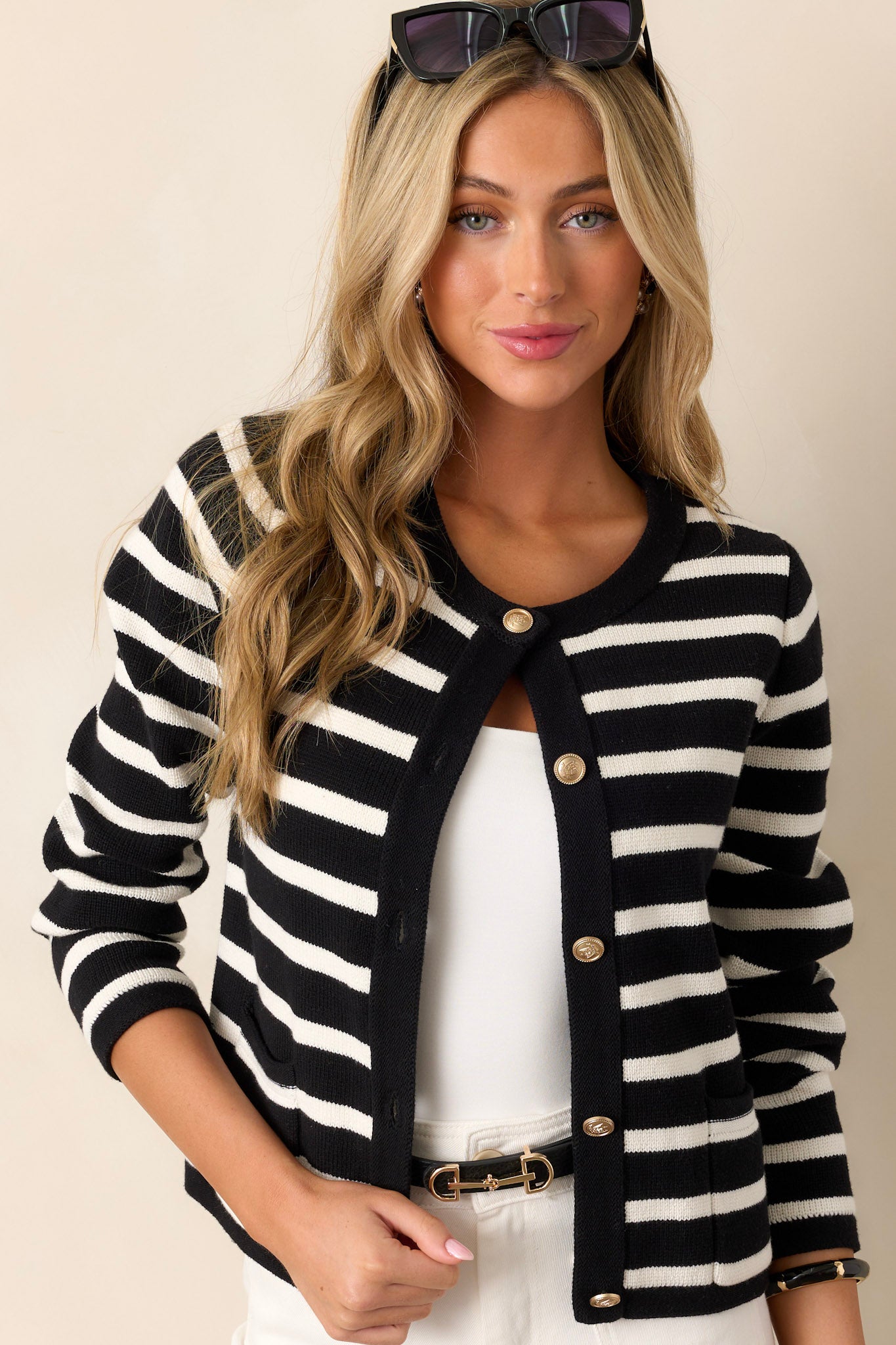 This cardigan features a crew neckline, a full button front, detailed gold buttons, and functional pockets.