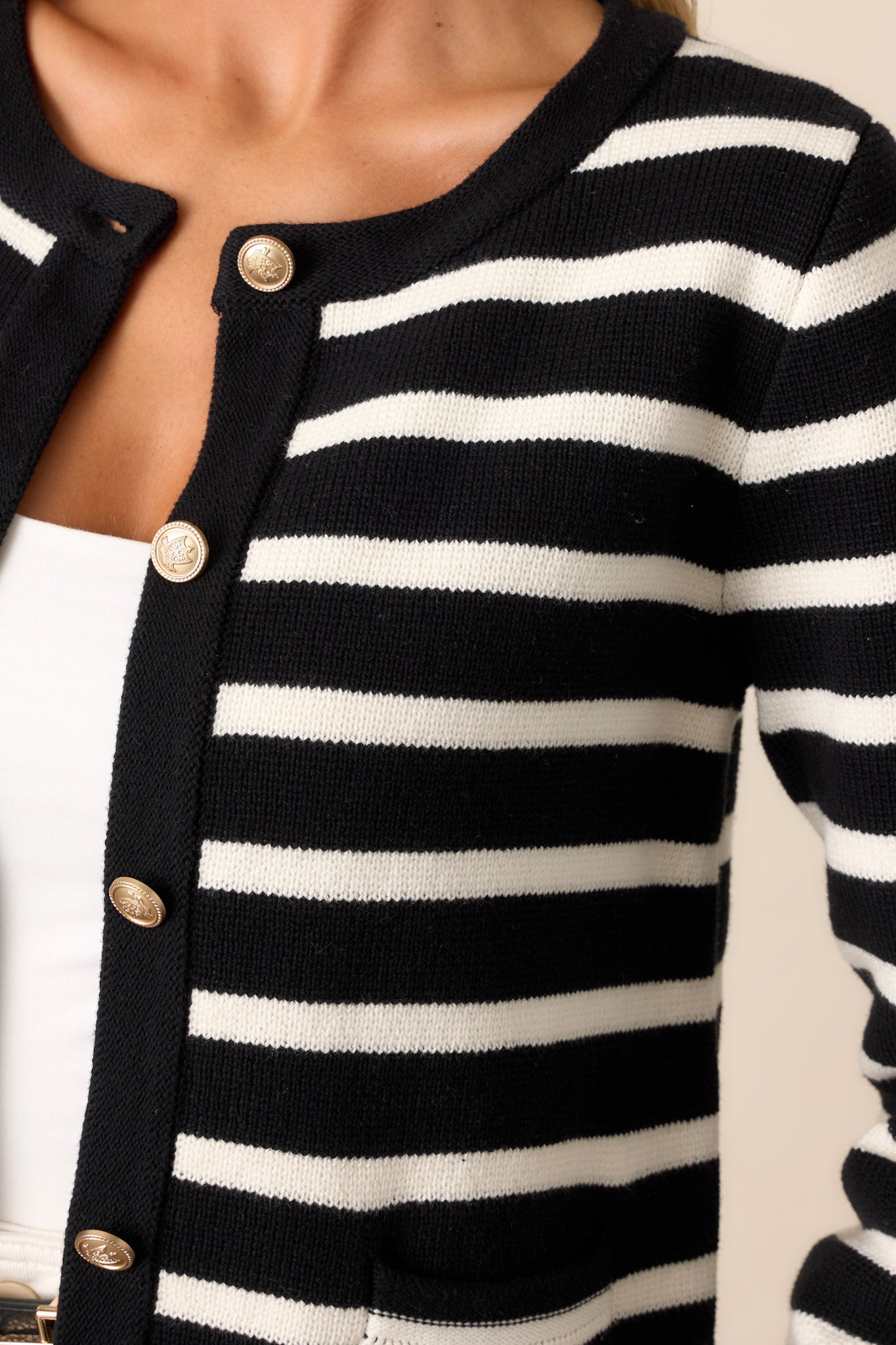 Close-up of the cardigan focusing on the crew neckline, detailed gold buttons, and the texture of the fabric around the functional pockets.