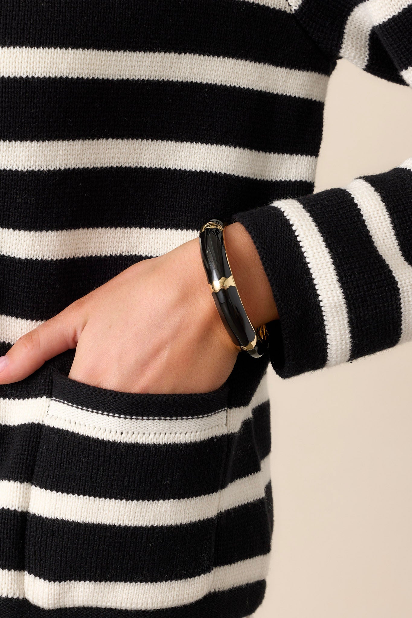 This hinged bracelet features a black and gold pattern, a gold inside and a hinge closure.