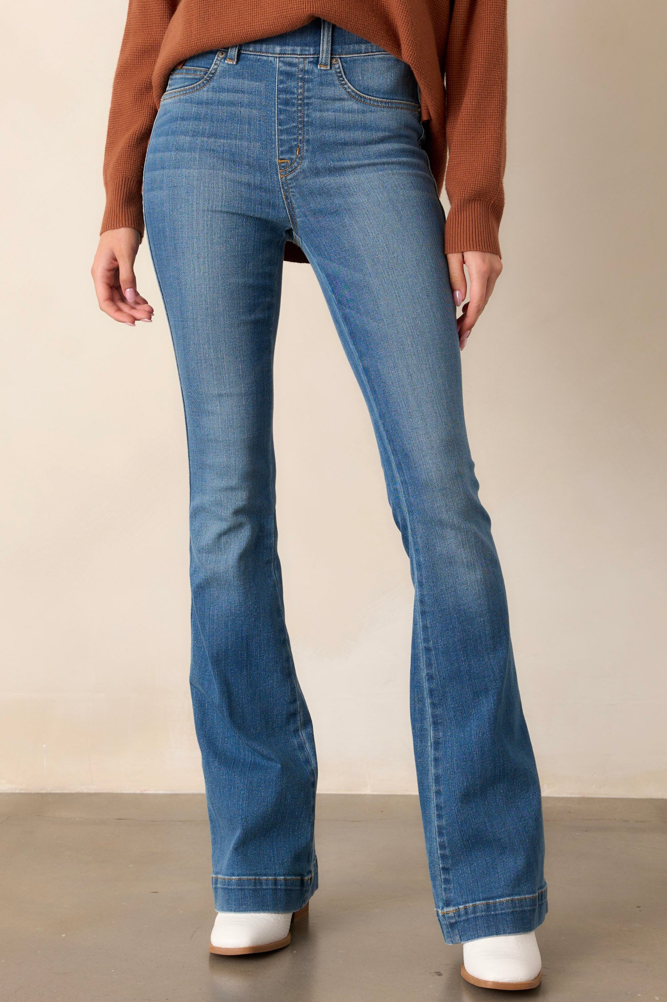 These indigo jeans feature a high waist, functional belt loops, slip on design, and a flared leg.